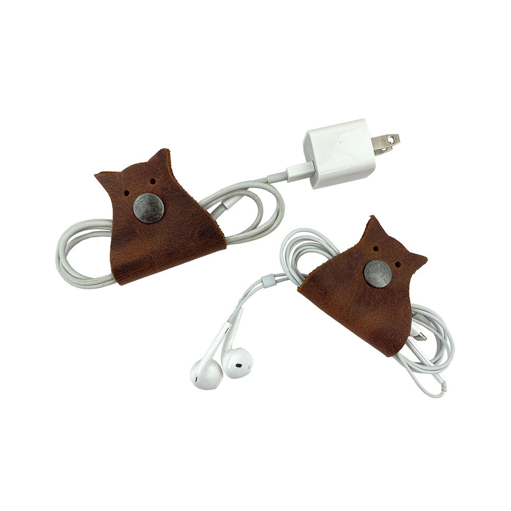Owl Shaped Cord Keeper (2-Pack) by Hide & Drink showing artisan-crafted organizers that bring charm and functionality to any workspace. Owl Shaped Cord Keeper (Cord Clam) 2-Pack. Full Grain Leather, StockyardX, Small Batch Production, Hand Cut, Hand Sewn, Fire Branded, Artisan, Handmade in La Antigua Guatemala & Oaxaca Mexico.