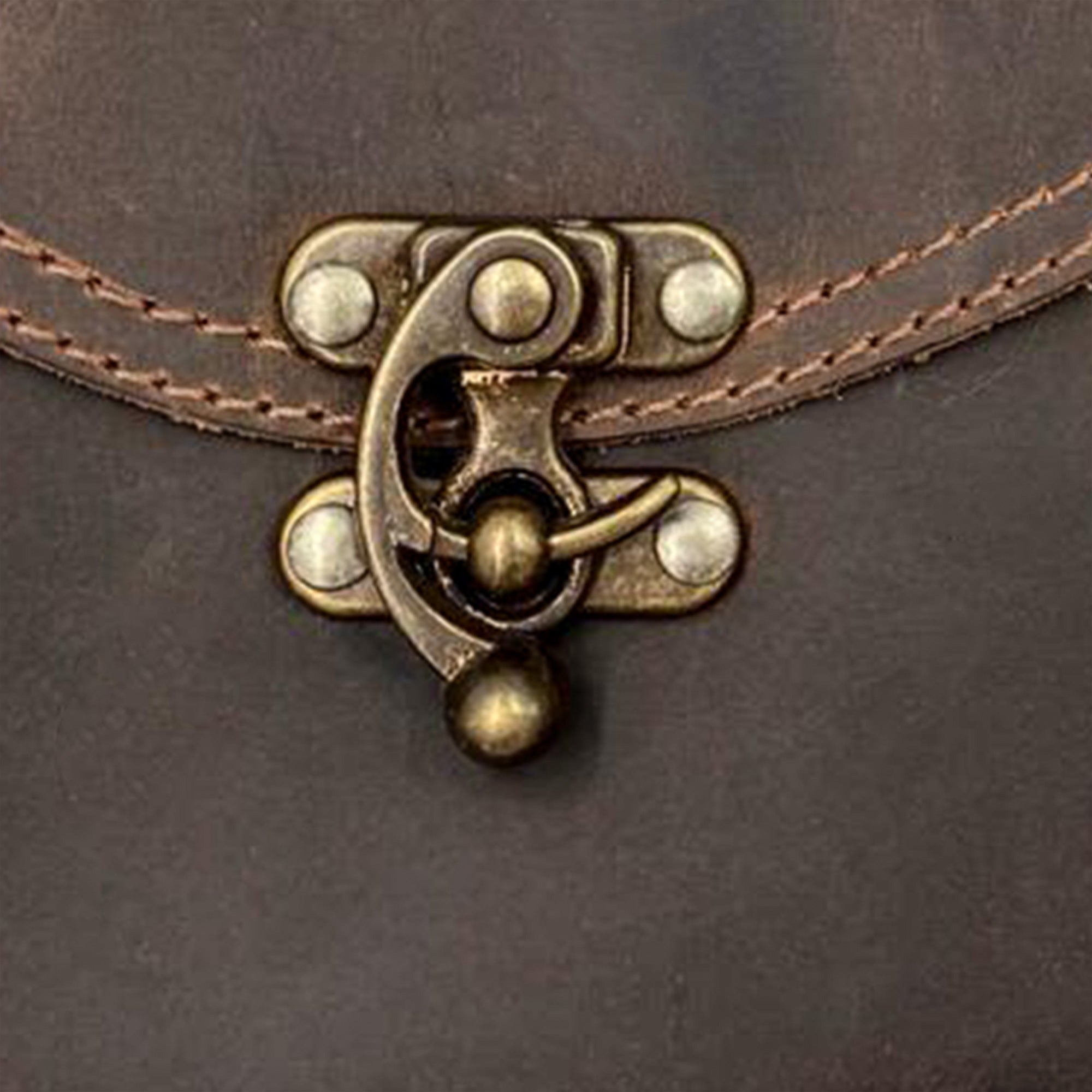 A close-up of the unique brass clasp on the Petite Vintage Clutch Bag by Hide & Drink, demonstrating high-quality craftsmanship. This elegant evening bag is made from durable full grain leather and is perfect for fashion enthusiasts who appreciate handmade artisan goods.