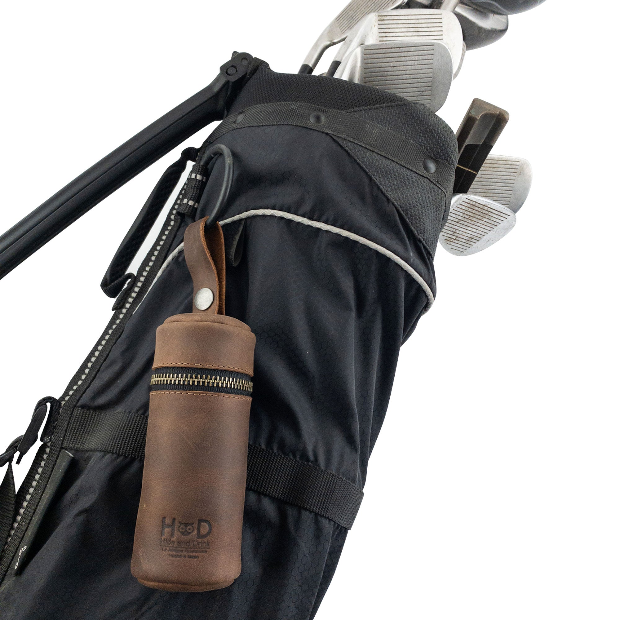Hide & Drink Cylinder Case for Golf Balls attached to a golf bag, illustrating its portability and convenience for golfers. Made from premium full grain leather, this handcrafted accessory features a sturdy hanger, representing the craftsmanship of small batch production from La Antigua Guatemala & Oaxaca Mexico.