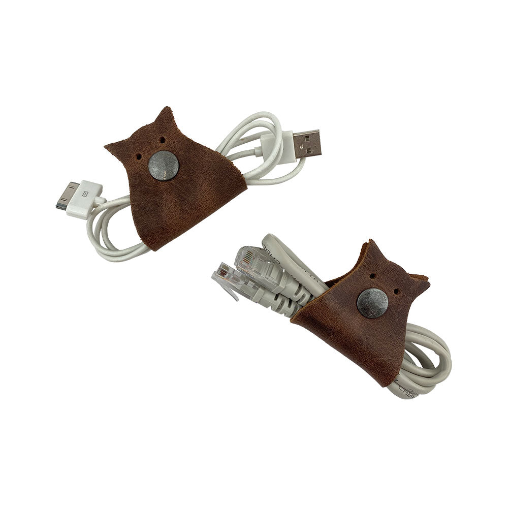 Functional Owl Shaped Cord Keeper (2-Pack) by Hide & Drink displaying a beautiful craftsmanship in leather and a unique owl design for cord organization. Owl Shaped Cord Keeper (Cord Clam) 2-Pack. Full Grain Leather, StockyardX, Small Batch Production, Hand Cut, Hand Sewn, Fire Branded, Artisan, Handmade in La Antigua Guatemala & Oaxaca Mexico.