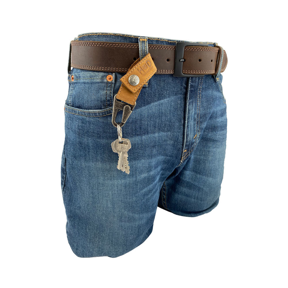 Hide & Drink Key Ring Holder displayed on denim shorts, showcasing a rustic leather design, made from Full Grain Leather. Hand Cut, Hand Sewn, and Fire Branded, this artisan piece embodies Small Batch Production, perfect for keeping your keys organized.