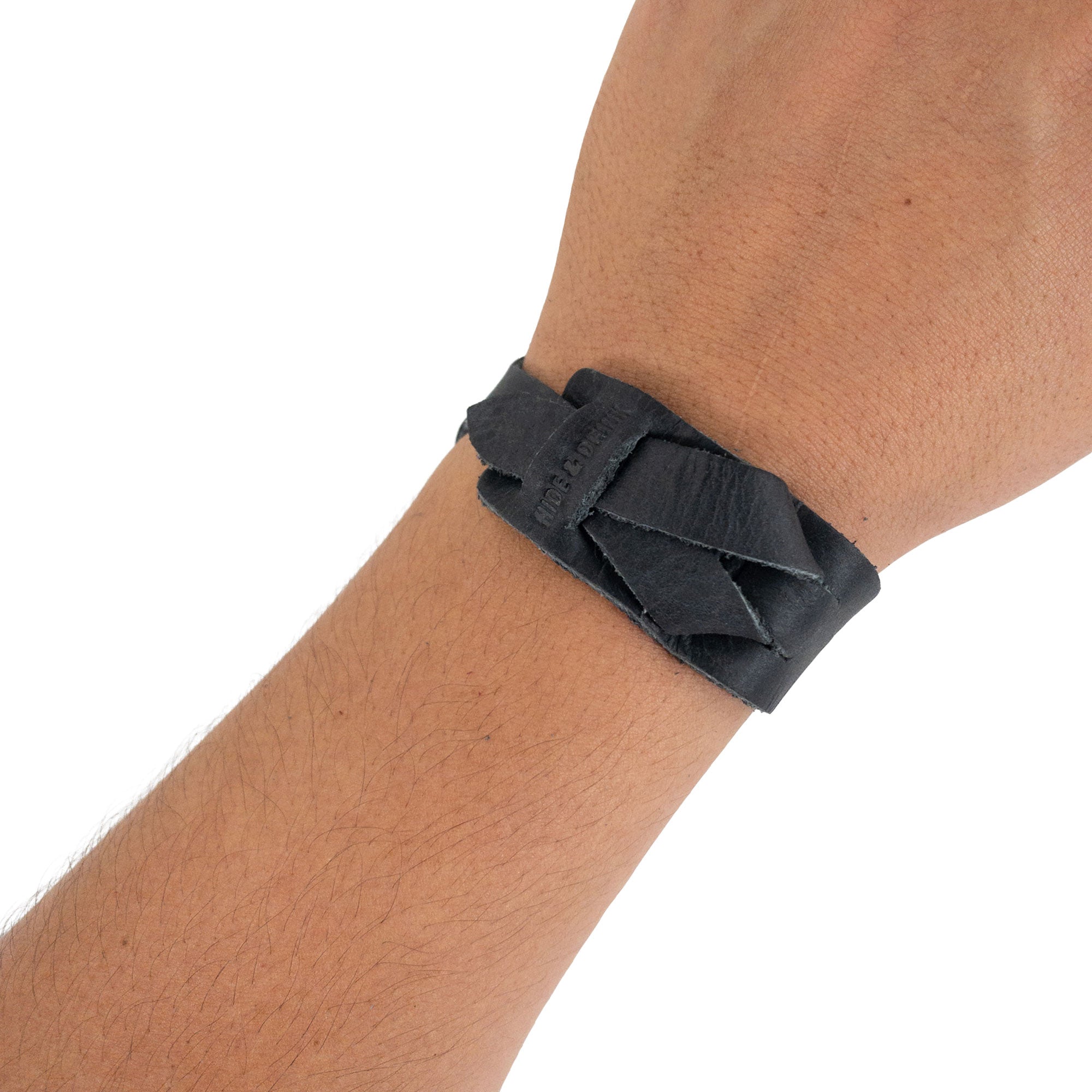 Hide & Drink's Minimalist Wristband on wrist, showcasing its stylish black leather design. This adjustable cuff reflects rugged elegance, handcrafted from full grain leather by artisans in La Antigua Guatemala, as part of StockyardX's rustic bracelet offerings.