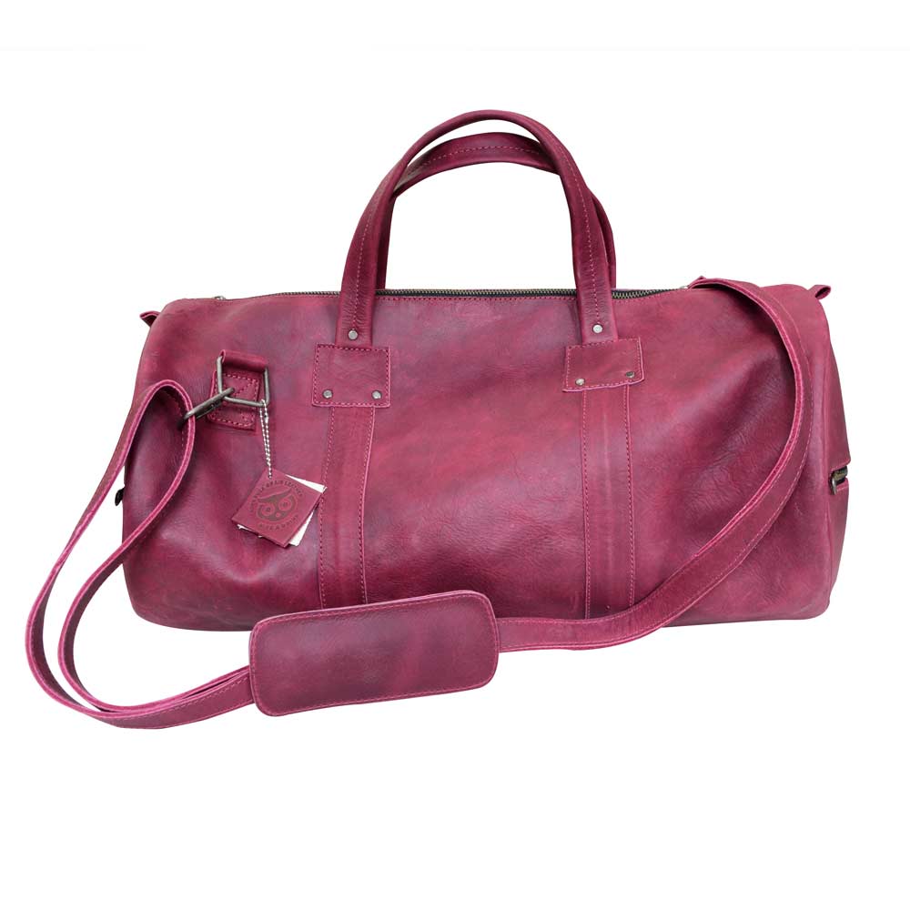 Classic Duffle Bag by Hide & Drink in vibrant pink, featuring a stylish design with a zipper closure and adjustable strap. The Full Grain Leather Classic Duffle Bag is perfect as a Messenger Bag for travel, handmade by artisans in La Antigua Guatemala & Oaxaca Mexico.