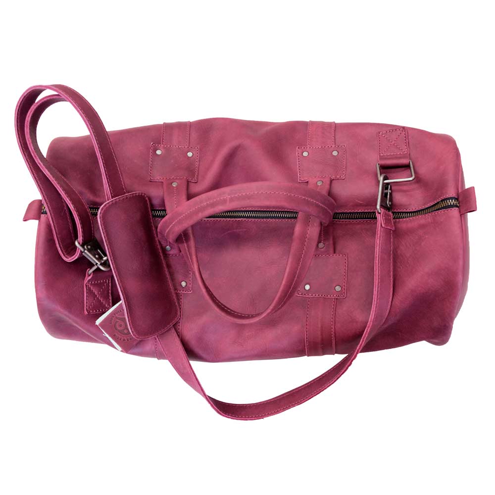 Top view of the Classic Duffle Bag by Hide & Drink in pink leather, showcasing its roomy interior and adjustable strap with zipper closure. This Full Grain Leather Classic Duffle Bag acts as a beautiful Messenger Bag for traveling needs, handcrafted in La Antigua Guatemala & Oaxaca Mexico.
