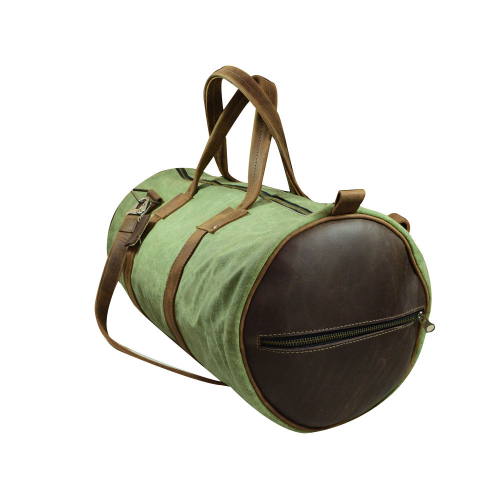 Side view of the Classic Duffle Bag by Hide & Drink in green with leather accents. This Full Grain Leather Classic Duffle Bag includes an adjustable strap and zipper closure, making it a perfect Messenger Bag for trips, handmade in La Antigua Guatemala & Oaxaca Mexico.