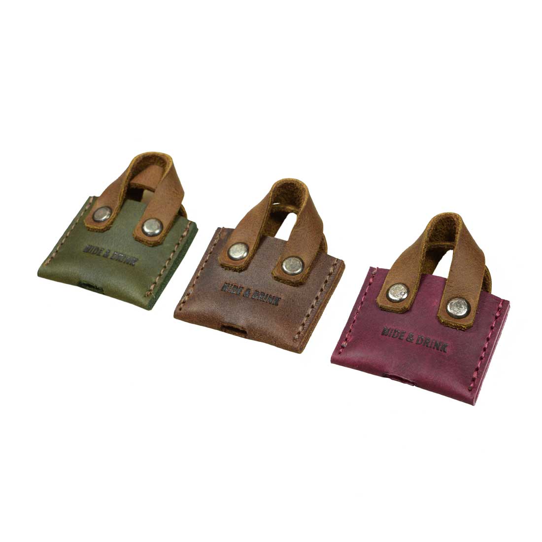 Hide & Drink's Mini Bags Key Cover (3 pack) displays another angle of colorful mini bag key covers in green, brown, and dark red. Each piece showcases the beauty of full grain leather, perfect for keychain organization and making thoughtful gifts, handmade with love in La Antigua Guatemala & Oaxaca Mexico.