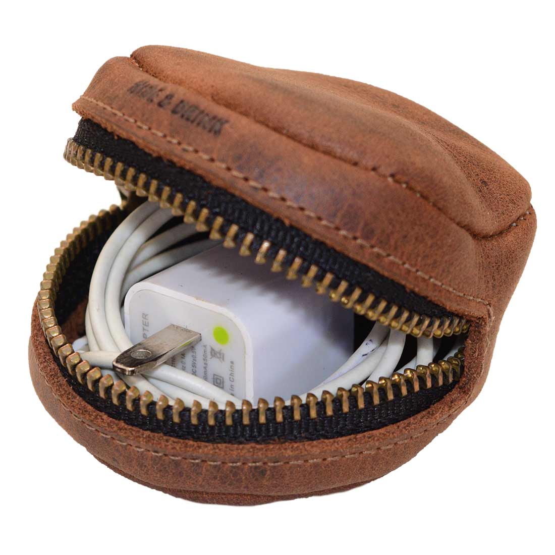 Hide & Drink Rounded Coin Case used to store a charger, highlighting its versatility. Made from Full Grain Leather through small batch production, this artisan piece is hand cut, hand sewn, and fire branded, reflecting quality craftsmanship from La Antigua Guatemala & Oaxaca Mexico.