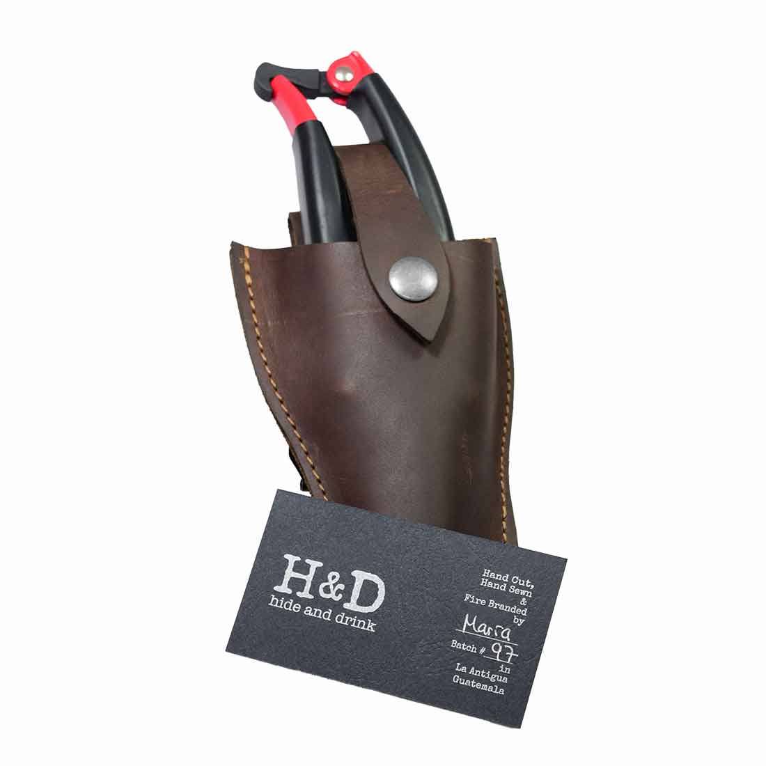 Hide & Drink Gardening Scissors Holster with initial packaging displaying branding and quality assurance. This handmade pruner sheath is crafted from full grain leather, perfect for ensuring your gardening tools are securely stored and easily accessible.