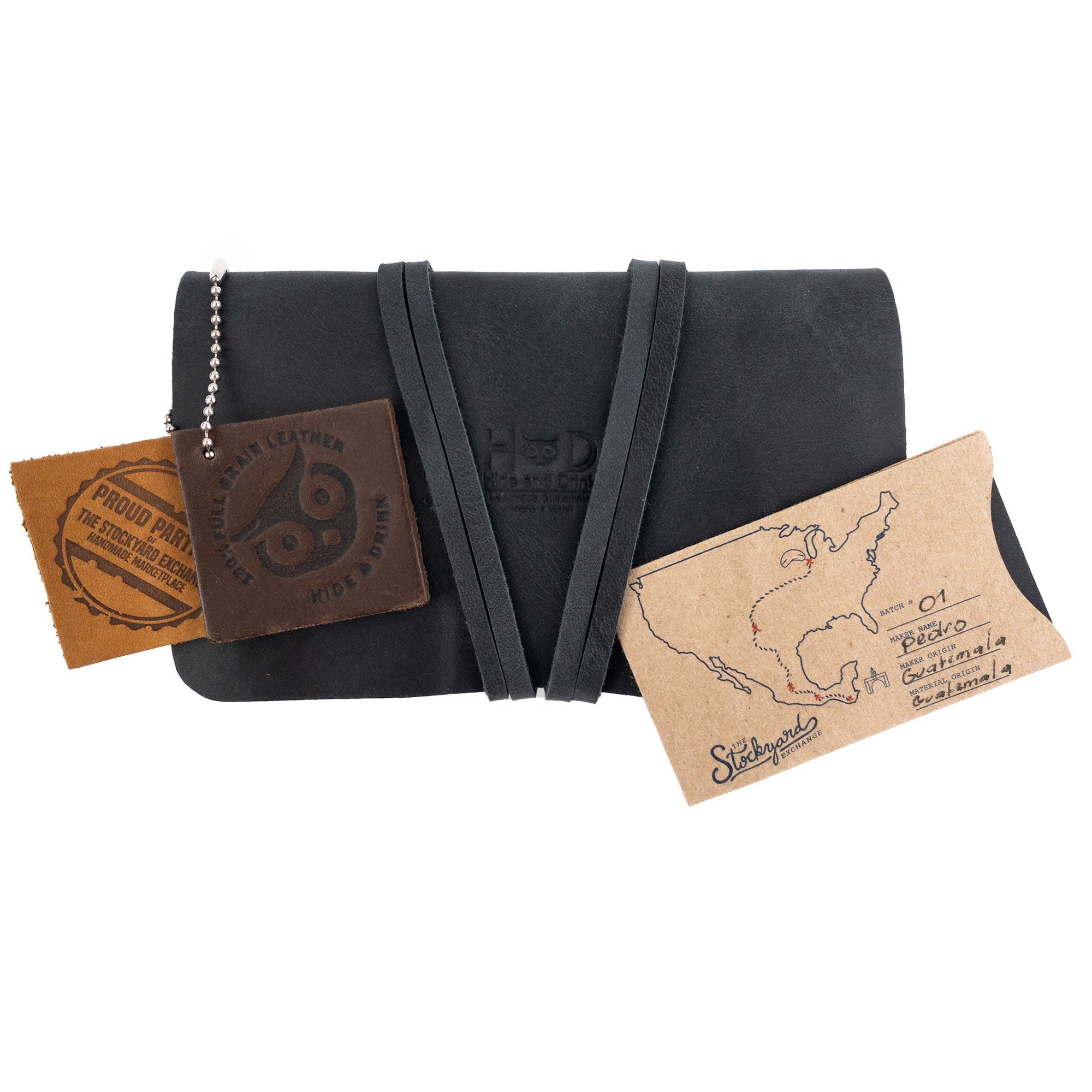 The elegant King Size Tobacco Pouch by Hide & Drink, featuring leather textures and tags that highlight its vintage storage potential. This full grain leather accessory is artisan handmade in La Antigua Guatemala.