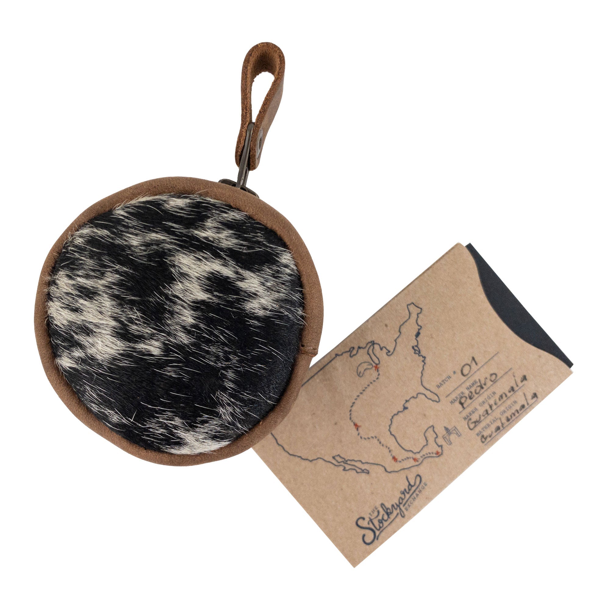 The Rounded Coin Case by Western Leather Works is styled alongside its packaging, highlighting its artisan credentials. The perfect accessory for organizing change or small gadgets, this pouch is a blend of beauty and utility. Handcrafted in La Antigua Guatemala, it represents exceptional small batch production.