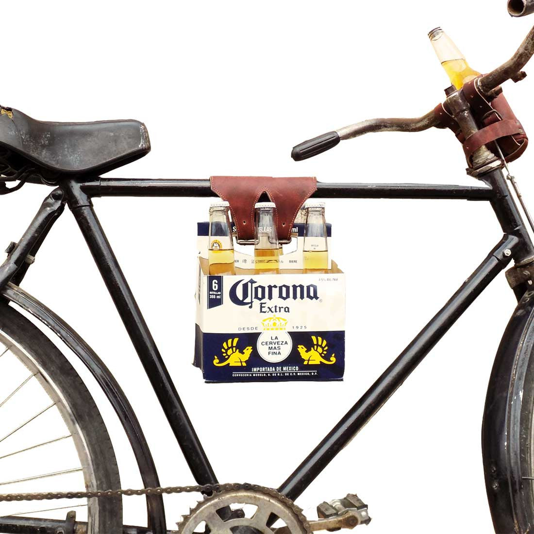A vintage bicycle featuring the Six-Pack Cinch by Hide & Drink, securely holding a six-pack of Corona beer. This stylish Bicycle Beer Carrier is made from Full Grain Leather and showcases artisan craftsmanship with hand cut and hand sewn details. A perfect accessory for biking enthusiasts, handmade in La Antigua Guatemala & Oaxaca Mexico.
