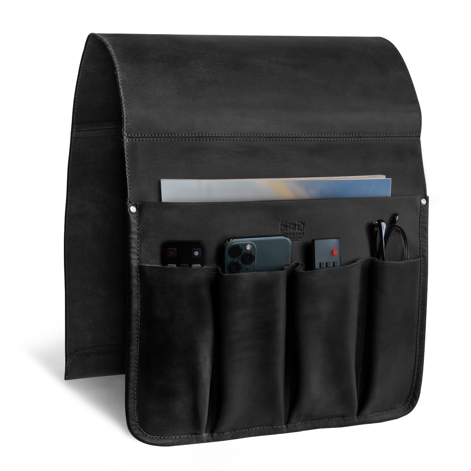 The side view of Hide & Drink‚Äôs Remote Control Holder in black leather demonstrates its pocket structure designed for efficient organization. This couch potato essential is ideal as an armchair caddy, merging style and functionality.