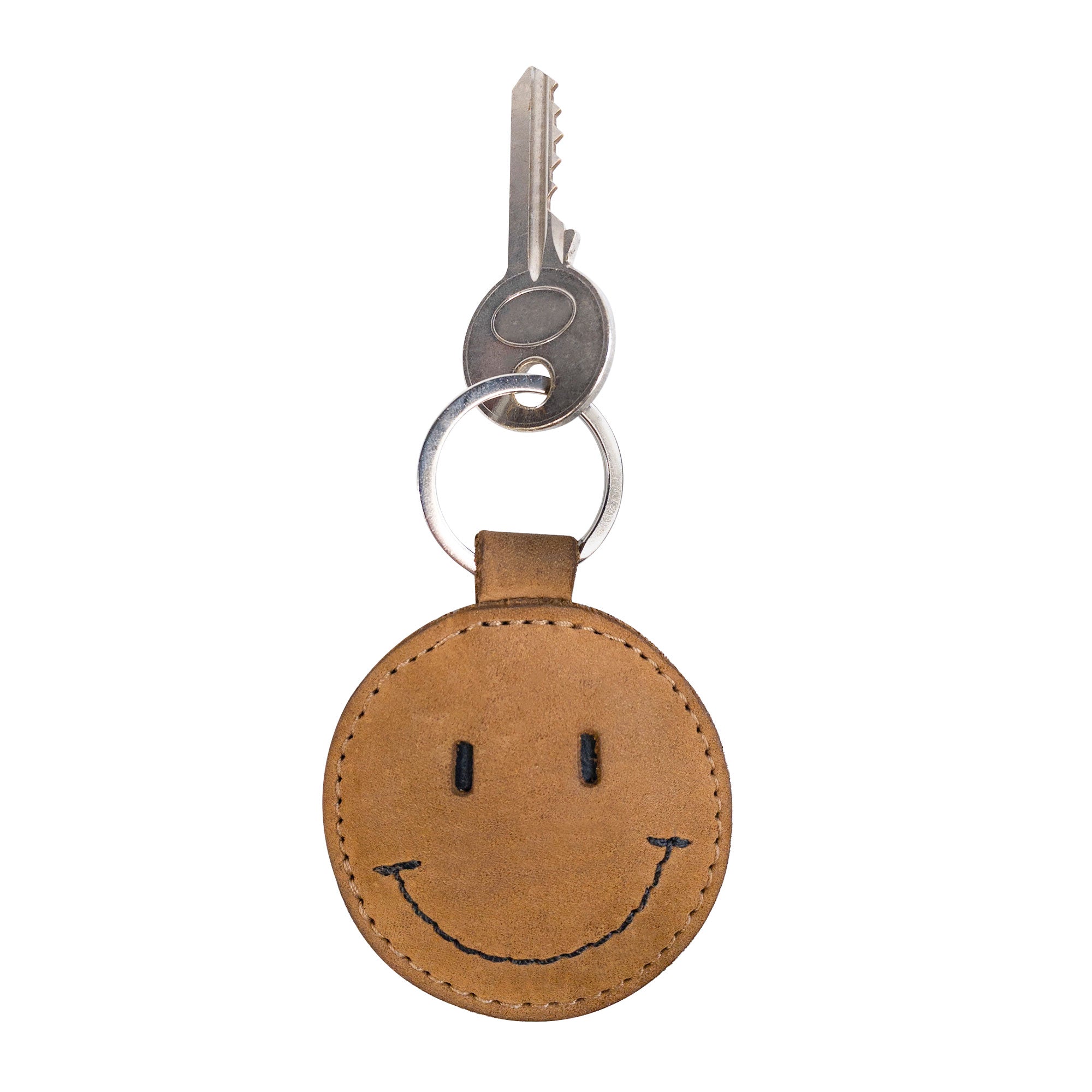 A close-up view of the Smiley Face Keychain by Hide & Drink, showcasing its cute design and attachment to a key ring. This handcrafted accessory is made from durable Full Grain Leather, making it a perfect addition to your keys. Ideal for cute gifts and accessories, featuring small batch production and artisan craftsmanship from La Antigua Guatemala.
