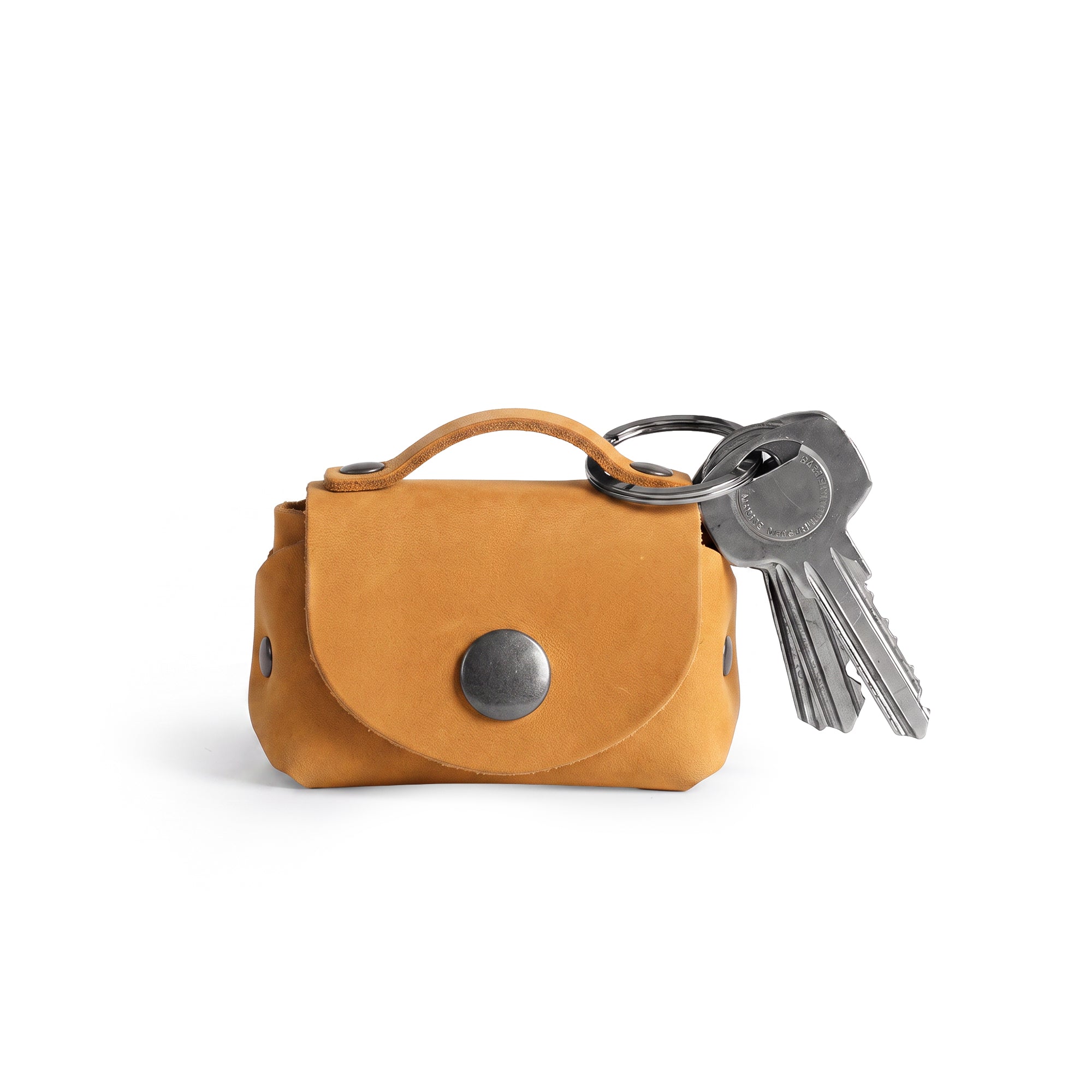 Side view of the Tiny Handbag Keychain by Hide & Drink in a beautiful mustard color, serving as a Tiny Handbag with Key Ring Holder made from Full Grain Leather. This artisan creation is a part of Small Batch Production, Hand Cut, Hand Sewn, and Fire Branded, showcasing the craftsmanship of being Handmade in La Antigua Guatemala & Oaxaca Mexico.