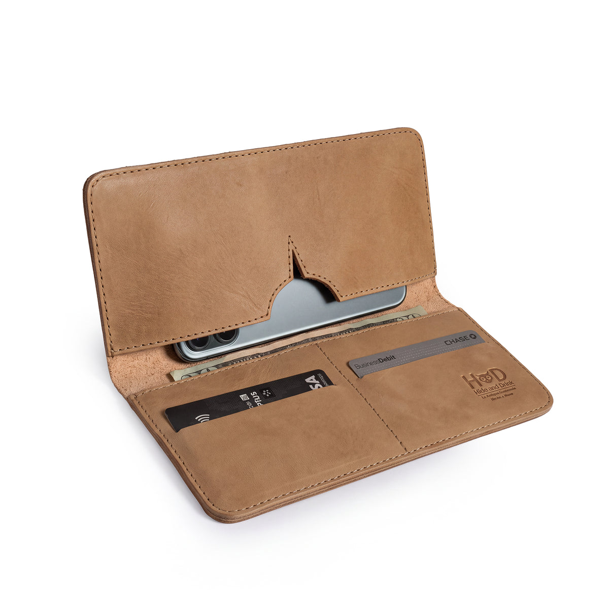 Open rustic bifold wallet for cellphone by Hide & Drink, showcasing compartments for cards and cash. This elegant Bifold Wallet for Cellphone is made of Full Grain Leather, ensuring durability and style. Discover the exquisite craftsmanship from small batch production in La Antigua Guatemala & Oaxaca Mexico.