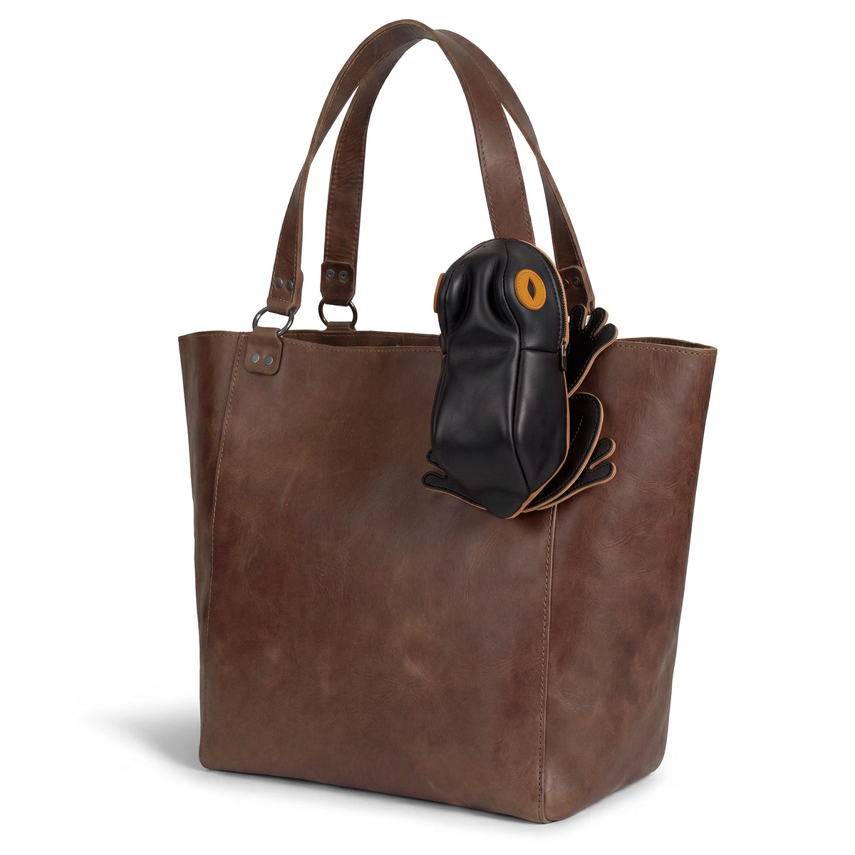 Tudi Frudi Frog Pouch displayed on a brown leather tote, showing the Frog-Shaped Pouch design as a Full Grain Leather Small Accessory Case, Cable Organizer, Zippered Cash Holder Wallet for Coins, Change Purse, and Pouches for Men and Women. StockyardX Small Batch Production, Hand Cut, Hand Sewn, Fire Branded, Artisan, Handmade in La Antigua Guatemala & Oaxaca Mexico.