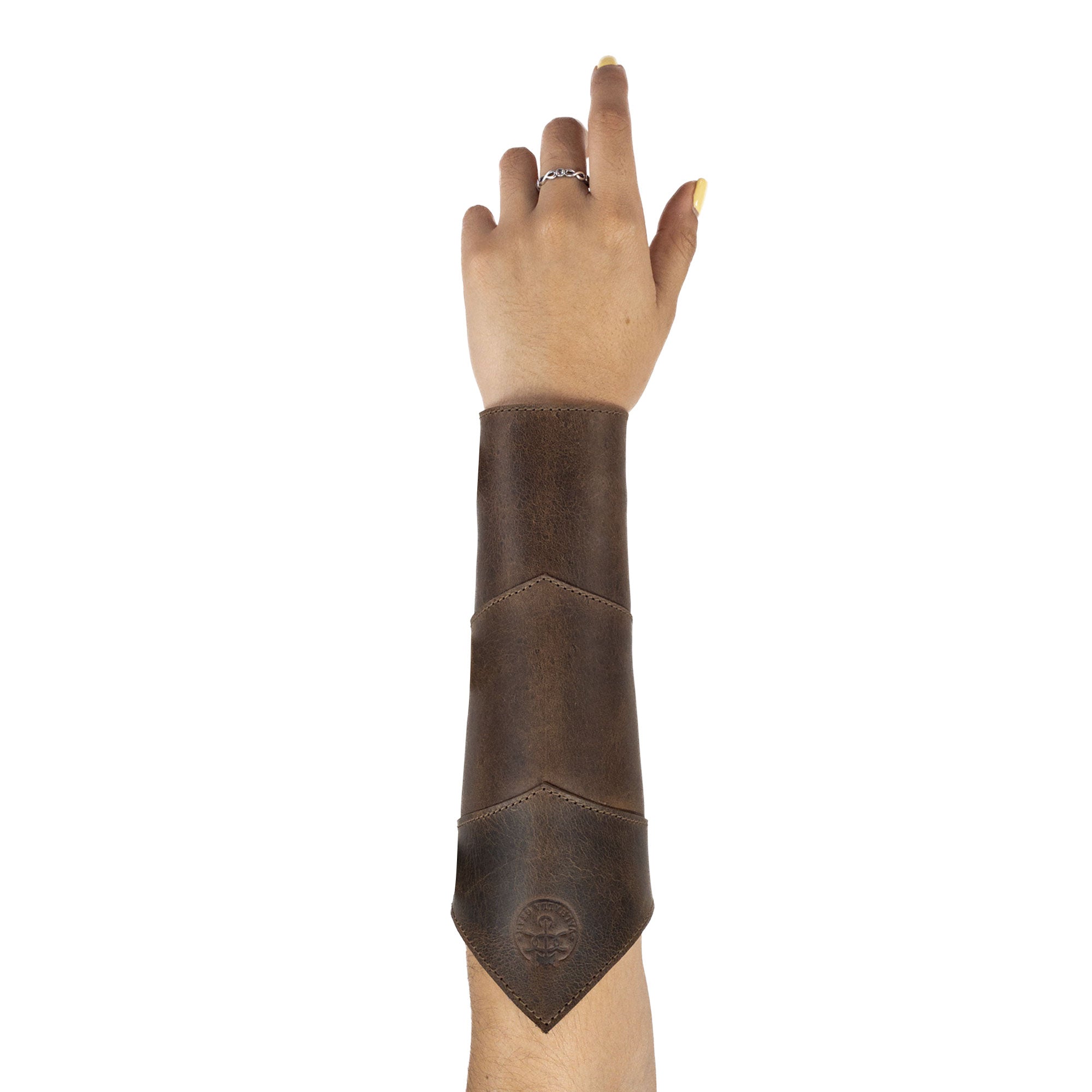 A hand wearing the Valhalla Gear Forearm Protector for Bow Shooting Practice, showcasing a comfortable Female Archery Bracer in rich brown full grain leather. This armband features adjustable buckle straps, making it ideal for cosplay and outdoor sessions, embodying small batch production quality, hand-cut and sewn craftsmanship, and artisan details distinct to La Antigua Guatemala.