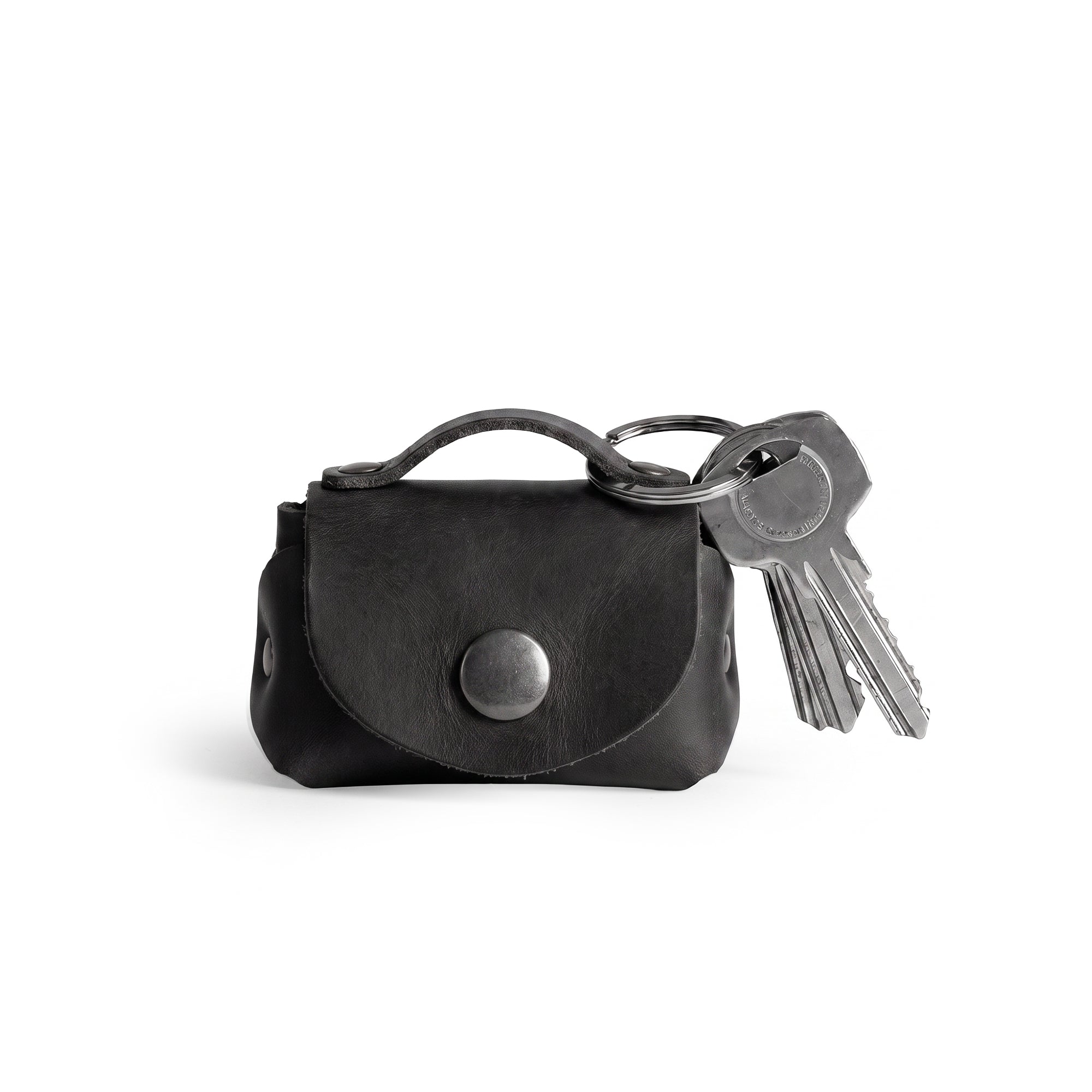 A stylish Tiny Handbag Keychain in black leather by Hide & Drink, featuring a key ring holder. This functional piece is made from high-quality Full Grain Leather and emphasizes small batch production and meticulous artisan craftsmanship.