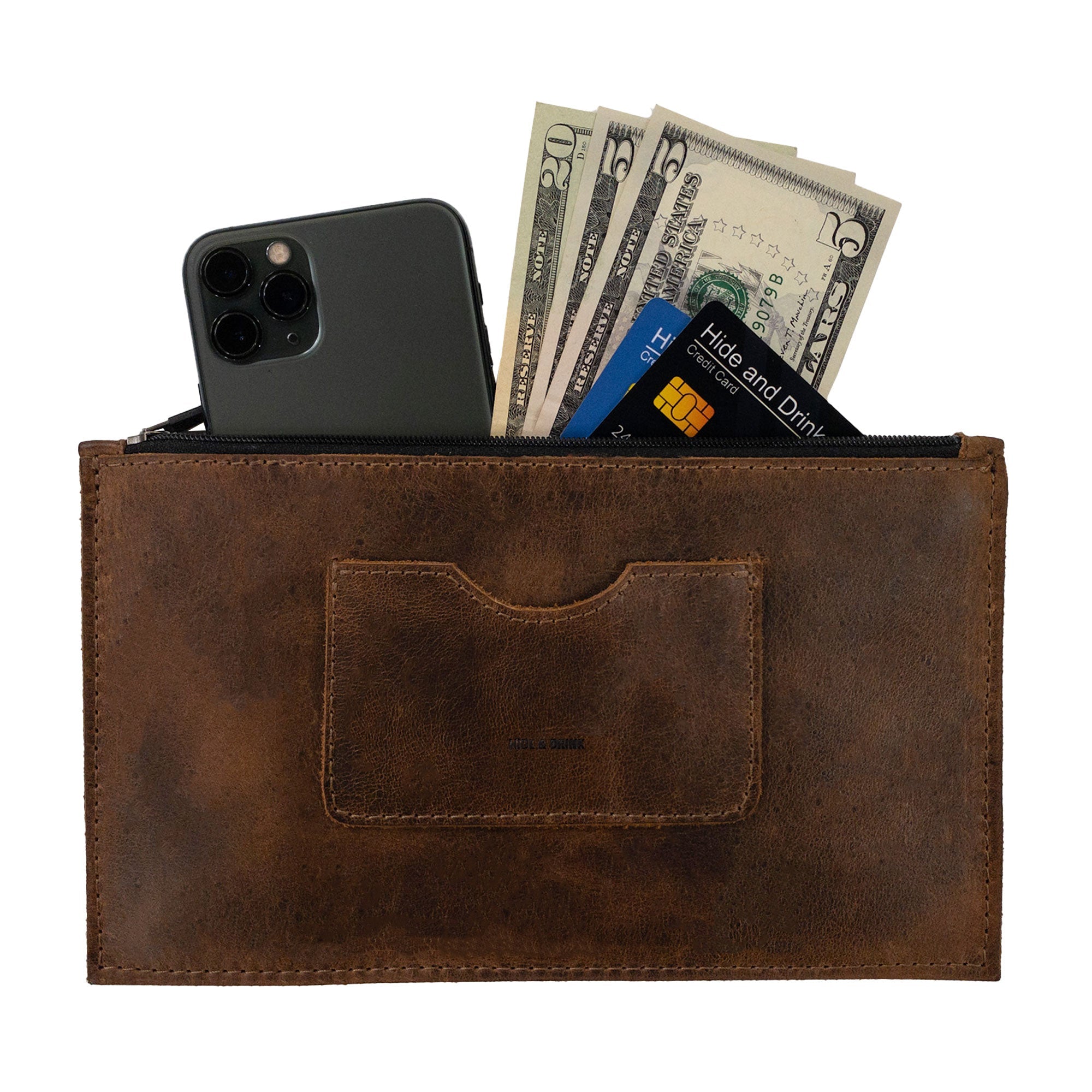 A brown rectangular zippered handbag by Hide & Drink, designed for women, featuring a card slot and filled with cash and a smartphone. This stylish female purse is crafted from durable full grain leather, and showcases the artisan craftsmanship with small batch production that's hand cut and sewn. A practical yet elegant accessory made in La Antigua Guatemala & Oaxaca Mexico.