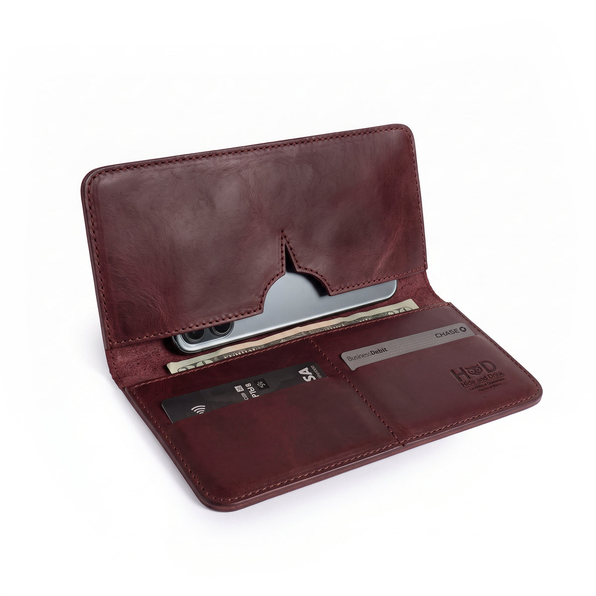 Open red bifold wallet for cellphone by Hide & Drink, showcasing card and cash compartments. This stylish Bifold Wallet for Cellphone is made from high-quality Full Grain Leather, perfect for effortless organization. Enjoy artisan craftsmanship with this handmade piece, produced in small batches in La Antigua Guatemala & Oaxaca Mexico.