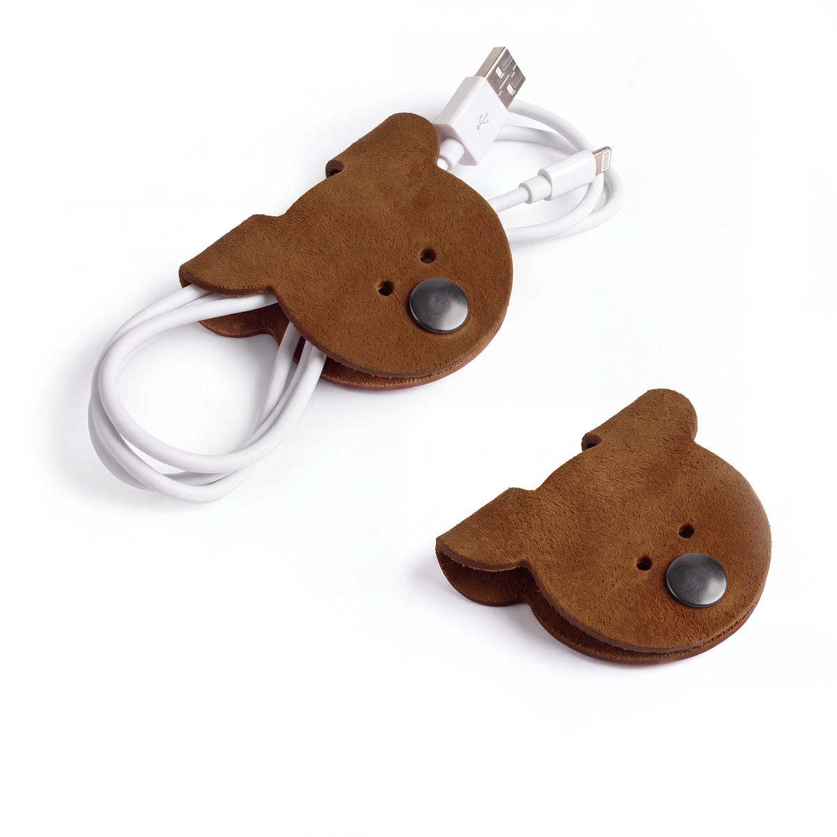 A pair of Bear Shaped Cord Keepers (Cord Clam) by Hide & Drink, featuring unique designs in Full Grain Leather, handmade and fire branded, perfect for keeping cords organized. Artisan crafted in La Antigua Guatemala & Oaxaca Mexico. Small Batch Production.