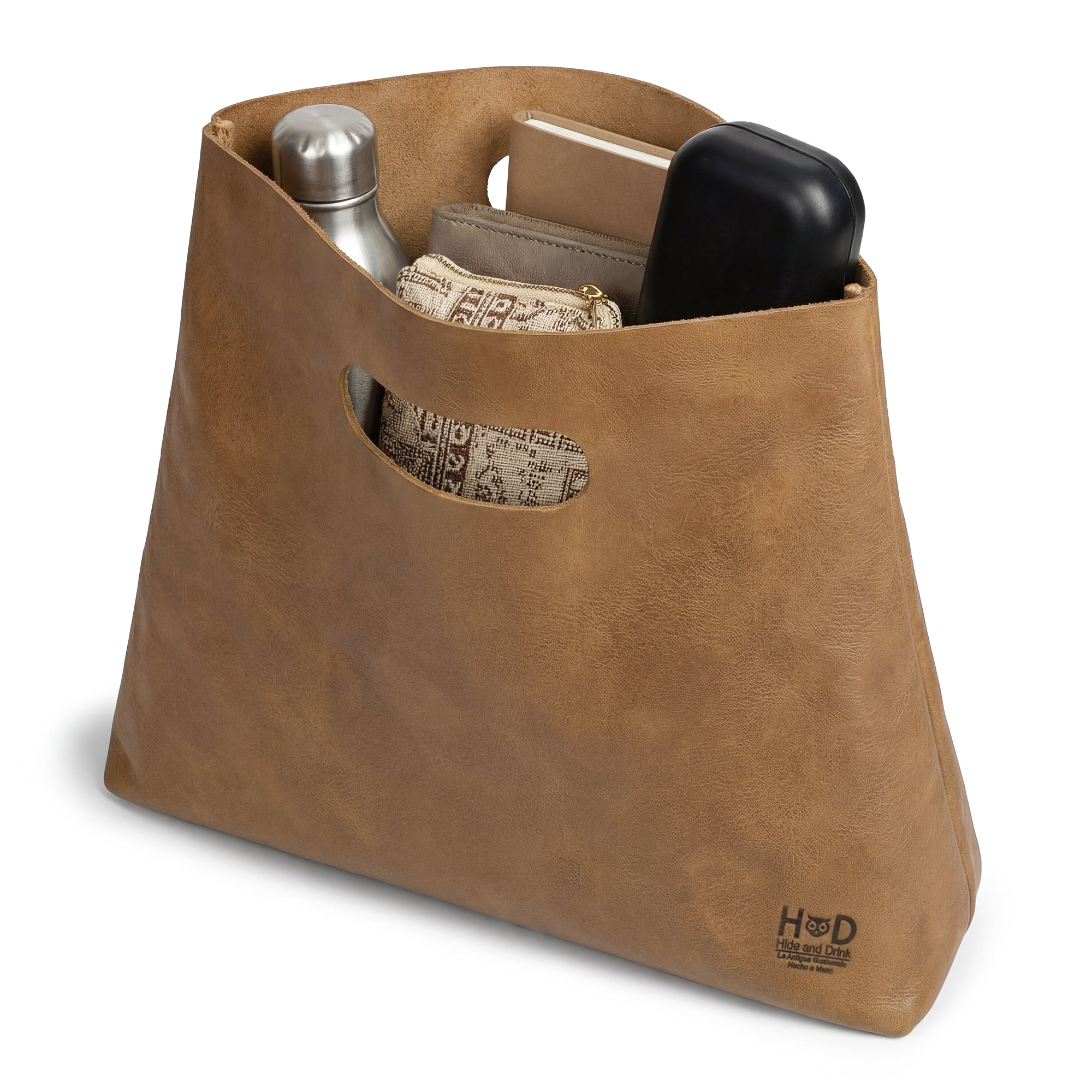The Minimalist Boho Handbag by Hide & Drink filled with items, showcasing its spacious interior. This functional and stylish Minimalist Handbag for Women is ideal as a Rustic Purse or Tote Bag, featuring the artisanal quality of Full Grain Leather.