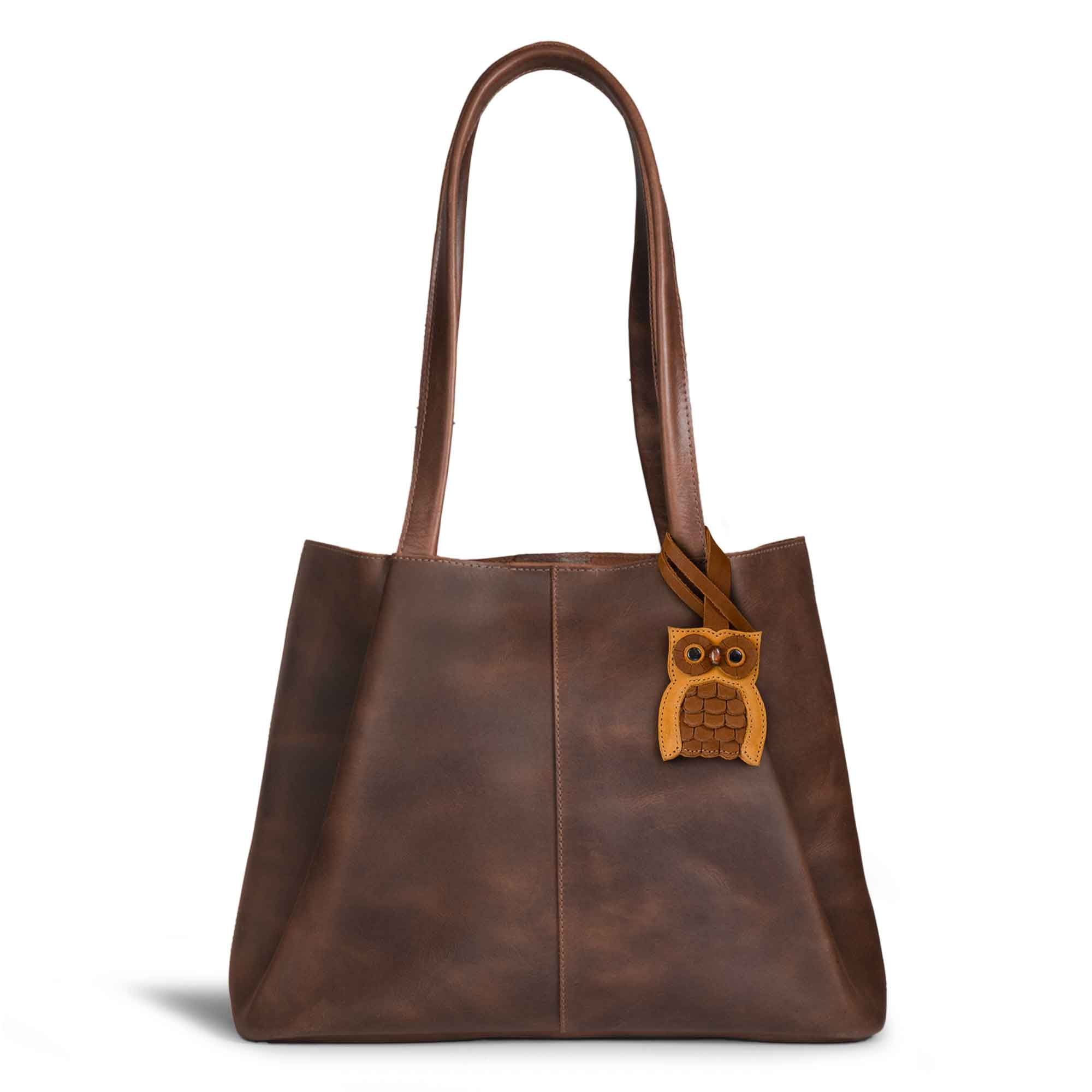 Hide & Drink Bag Charms attached to a trendy brown handbag, featuring a fox design ideal for personalization. This accessory acts as a purse charm for tote & backpacks crafted from premium full grain leather, showcasing StockyardX's commitment to small batch production. Every piece highlights meticulous hand cut, hand sewn artistry and fire branding, handmade in La Antigua Guatemala & Oaxaca Mexico.