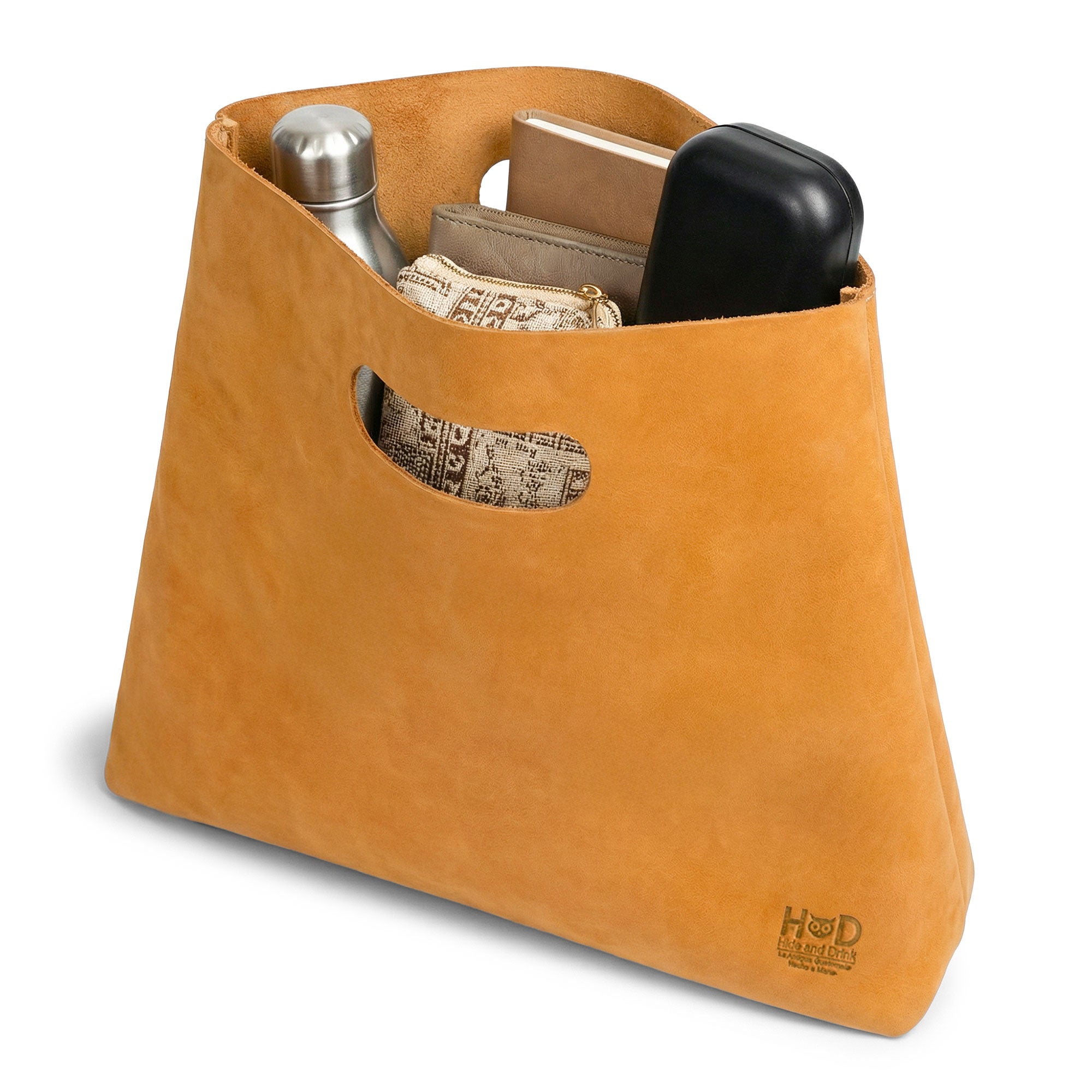 Angle view of the Minimalist Boho Handbag by Hide & Drink, focusing on its unique opening and seamless design. This Minimalist Handbag for Women serves as a reliable Tote Bag or Rustic Purse, crafted from durable Full Grain Leather. Handmade with care in La Antigua Guatemala and Oaxaca Mexico, it features a fire branded logo and showcases small batch production.