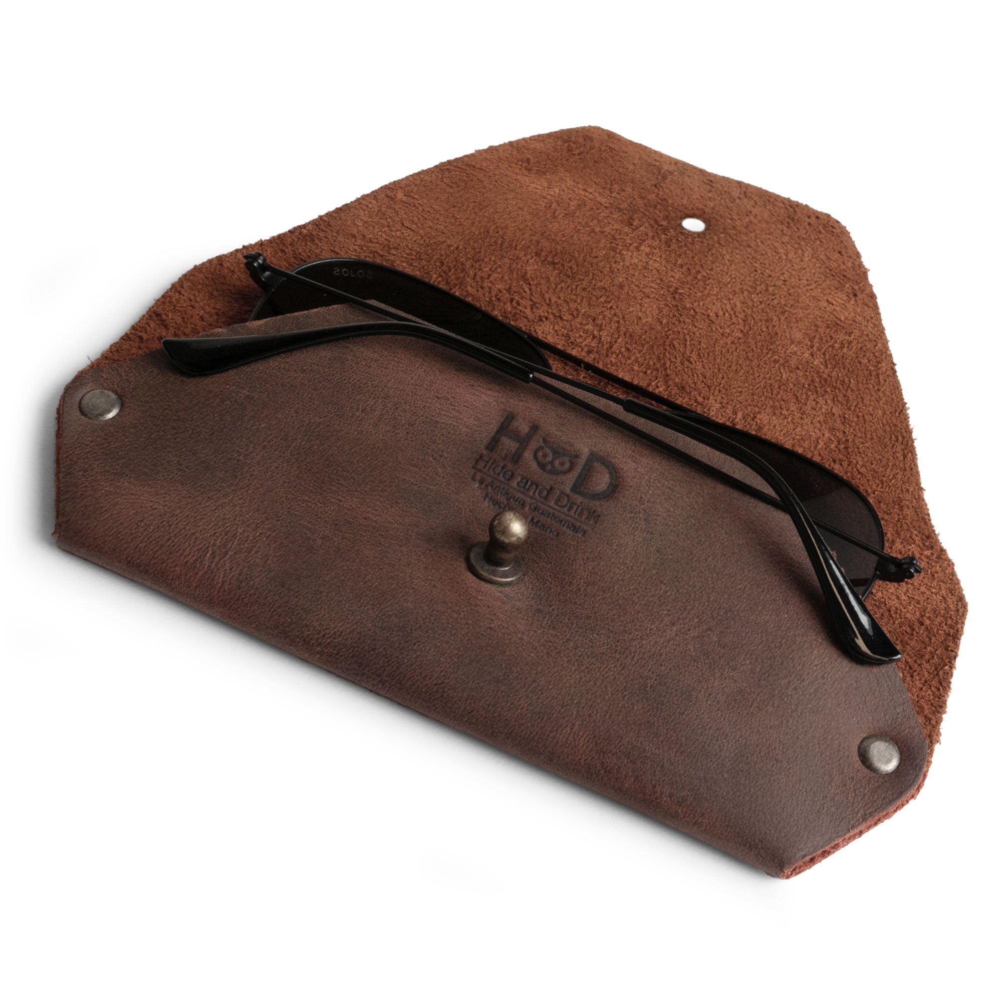 The Sunglasses Sleeve from Hide & Drink, shown with sunglasses inside, illustrates the elegant minimalist sleeve case protector for eyewear. Made from full grain leather, this product is ideal for outdoor enthusiasts and travelers alike. With its artisan handmade quality, including small batch production, hand cut, hand sewn, and fire branded finish, it exemplifies fine craftsmanship from La Antigua Guatemala.