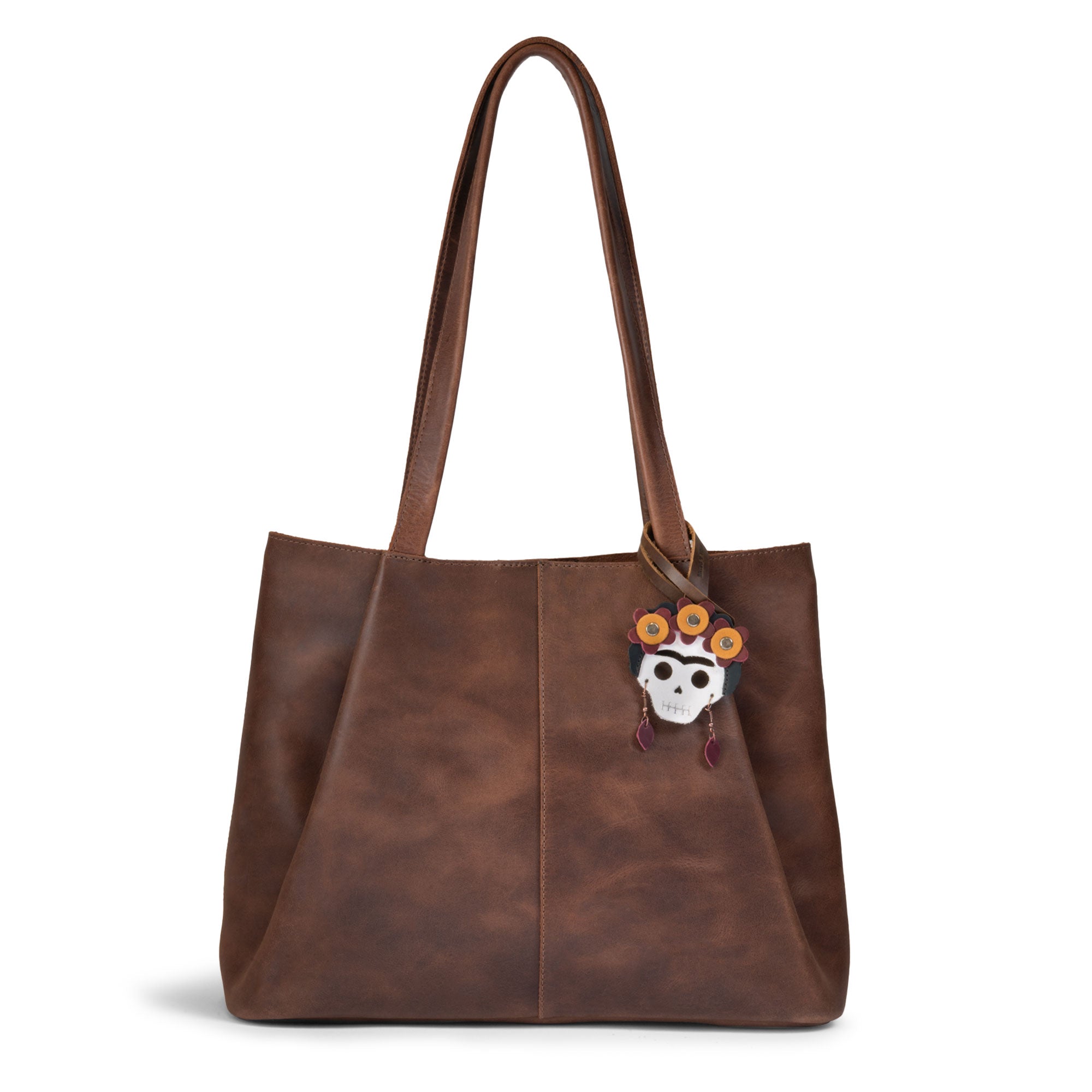 Hide & Drink Bag Charms attached to a stylish brown handbag, showcasing a strawberry design perfect for personalization. This purse charm for tote & backpacks made from durable full grain leather reflects StockyardX's dedication to small batch production, featuring hand cut, hand sewn craftsmanship and fire branding, handmade in La Antigua Guatemala & Oaxaca Mexico.