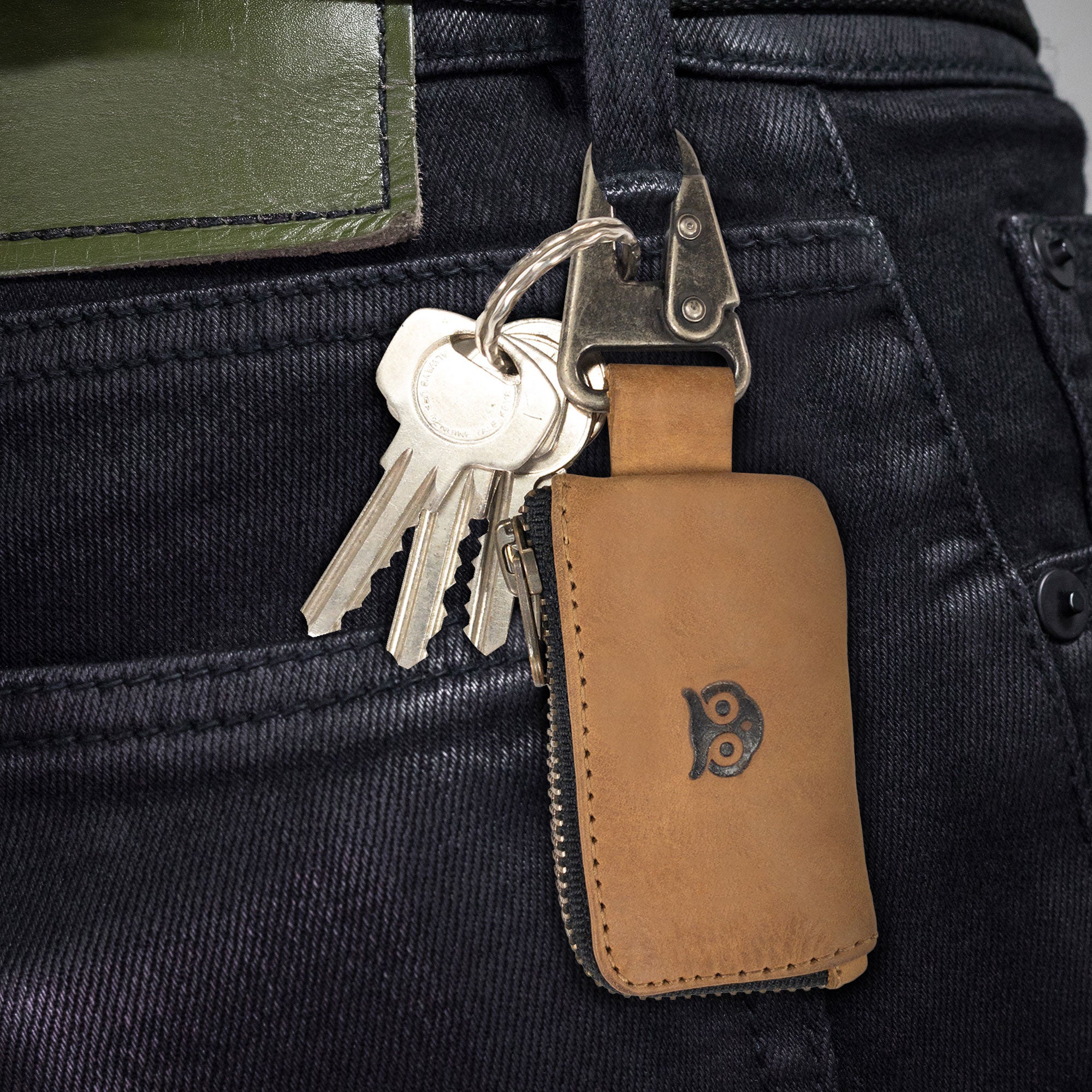 Side view of the brown Car Key Holder by Hide & Drink, showcasing its versatility for securely holding keys and cash while accommodating Headphone and charging Cables, Memory Cards, and Flash Drives. Made of high-quality Full Grain Leather with a Nickel Metal Clasp, displaying artisan craftsmanship from Small Batch Production in La Antigua Guatemala & Oaxaca Mexico.