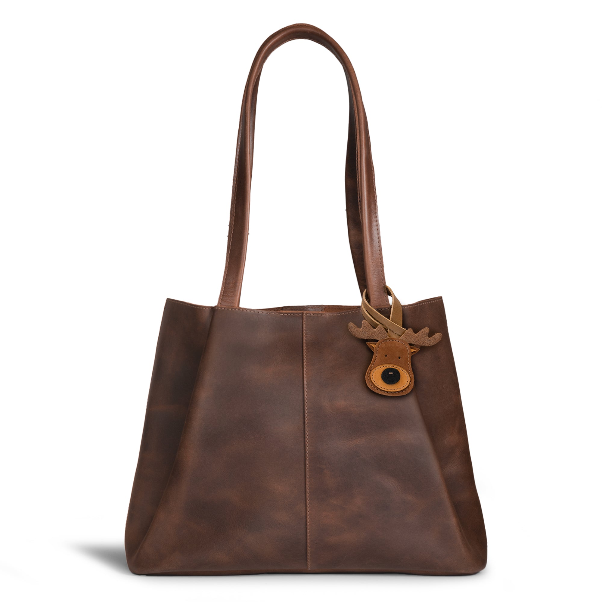 Hide & Drink Bag Charms attached to a stylish brown handbag, showcasing a dolphin design perfect for personalization. This accessory serves as a purse charm for tote & backpacks made from durable full grain leather, reflecting StockyardX's focus on small batch production. Every piece features hand cut, hand sewn artistry and fire branding, handmade in La Antigua Guatemala & Oaxaca Mexico.