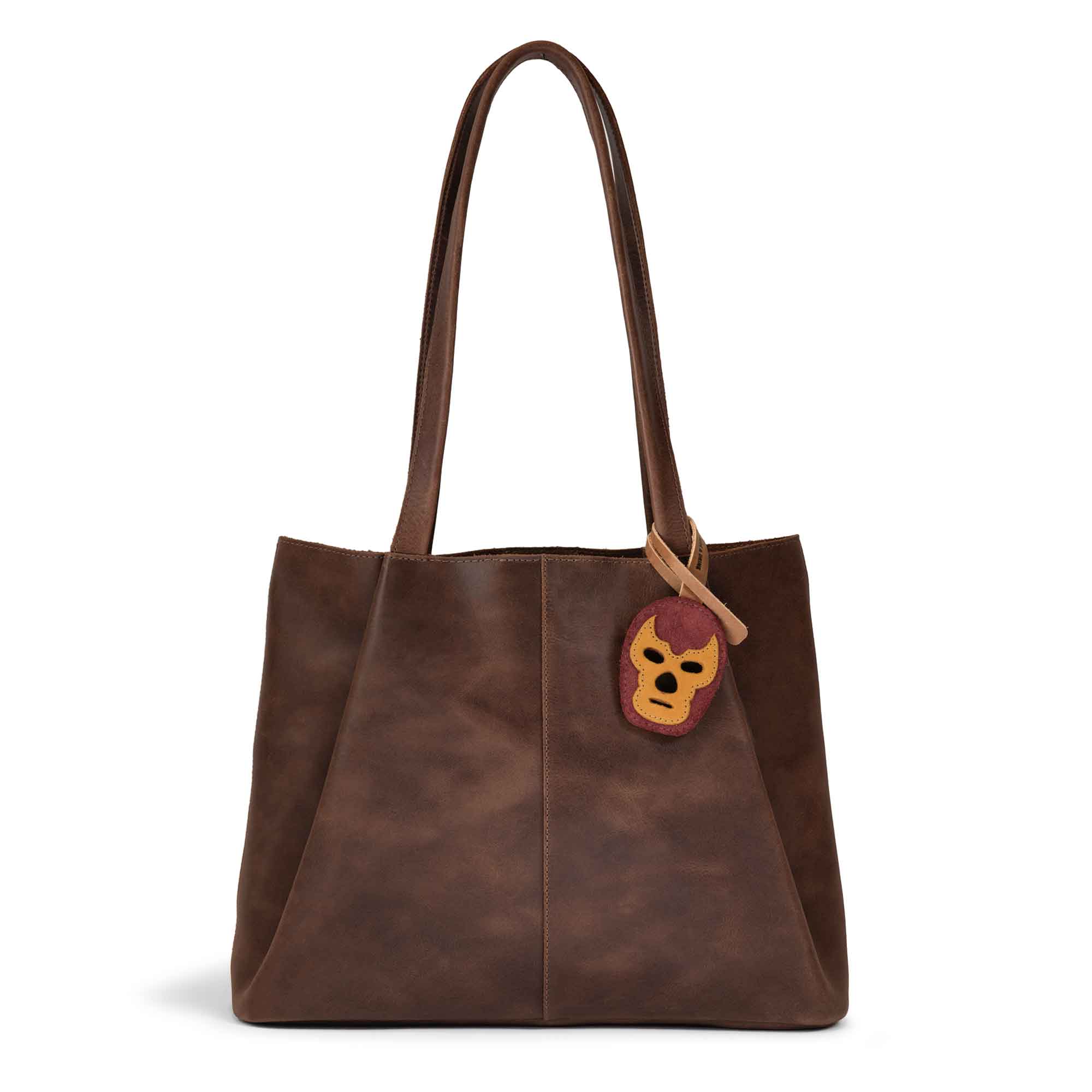 Hide & Drink Bag Charms attached to a stylish brown handbag, showcasing an owl design perfect for personalization. This accessory serves as a purse charm for tote & backpacks crafted from high-quality full grain leather. Every piece reflects StockyardX's commitment to small batch production, showcasing hand cut, hand sewn artistry and fire branding, handmade in La Antigua Guatemala & Oaxaca Mexico.