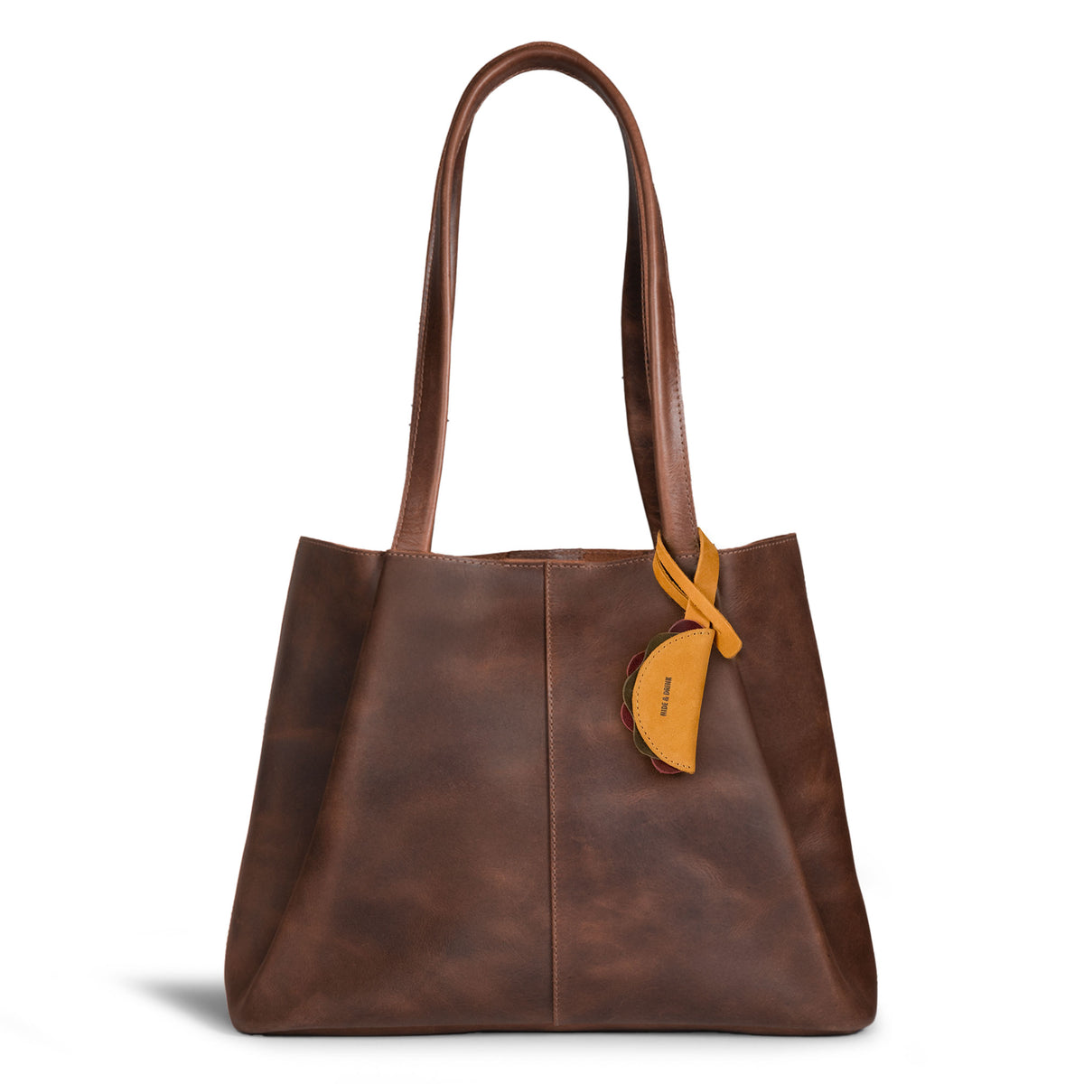 Hide & Drink Taco Bag Charm displayed on a brown leather tote, showcasing a Full Grain Leather Artisan accessory made through Small Batch Production, Hand Cut, Hand Sewn, and Fire Branded craftsmanship, Handmade in La Antigua Guatemala & Oaxaca Mexico, from StockyardX.