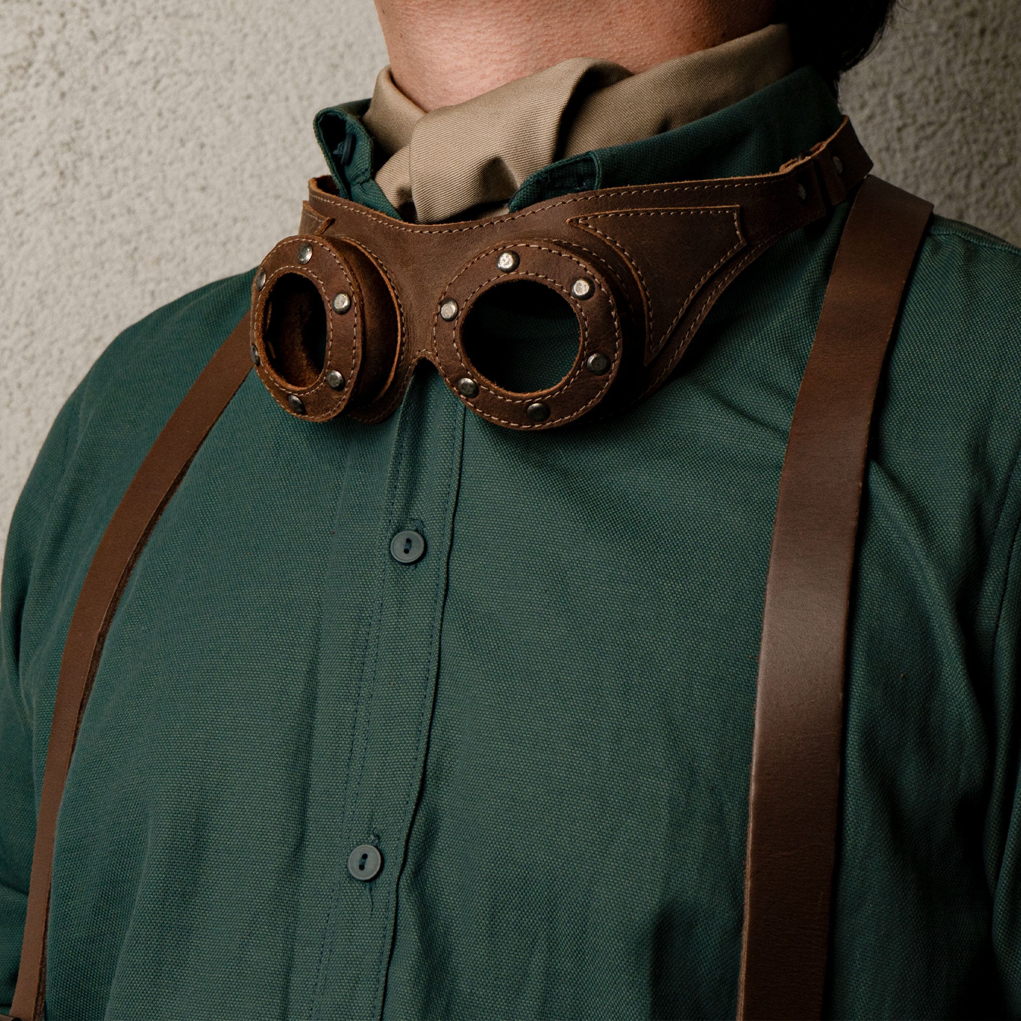 A model wearing Riveted Steampunk Goggles by Hide & Play, capturing the unique style of this costume accessory. Made from full grain leather, these retro goggles serve as a striking cosplay prop, emphasizing the artisan quality and handmade processes in La Antigua Guatemala.