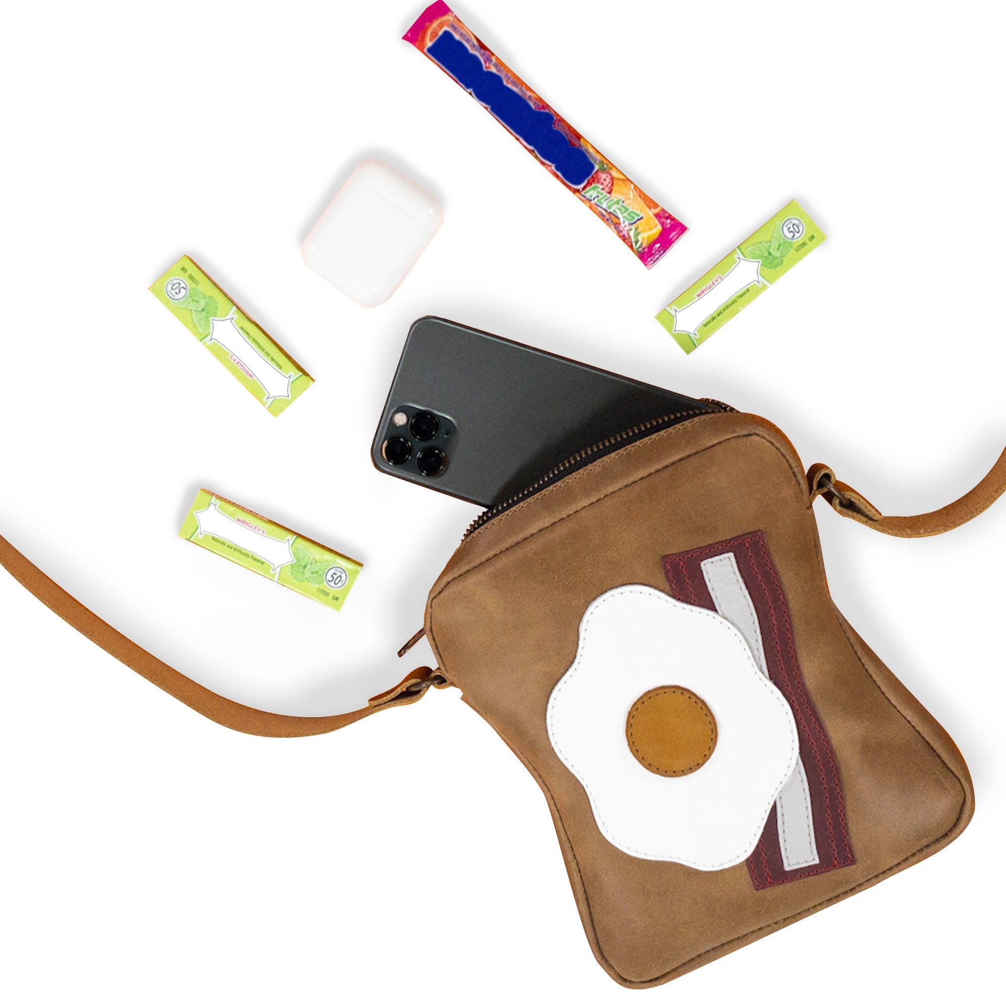 The Egg and Bacon Sandwich-Shaped Shoulder Bag by Tudi Frudi featuring a smartphone inside, offering a glimpse of its spacious design and practicality. Ideal as a Handbag, Crossbody Bag, or Messenger Bag, crafted from Full Grain Leather with precise artisanship, Handmade in La Antigua Guatemala & Oaxaca Mexico.