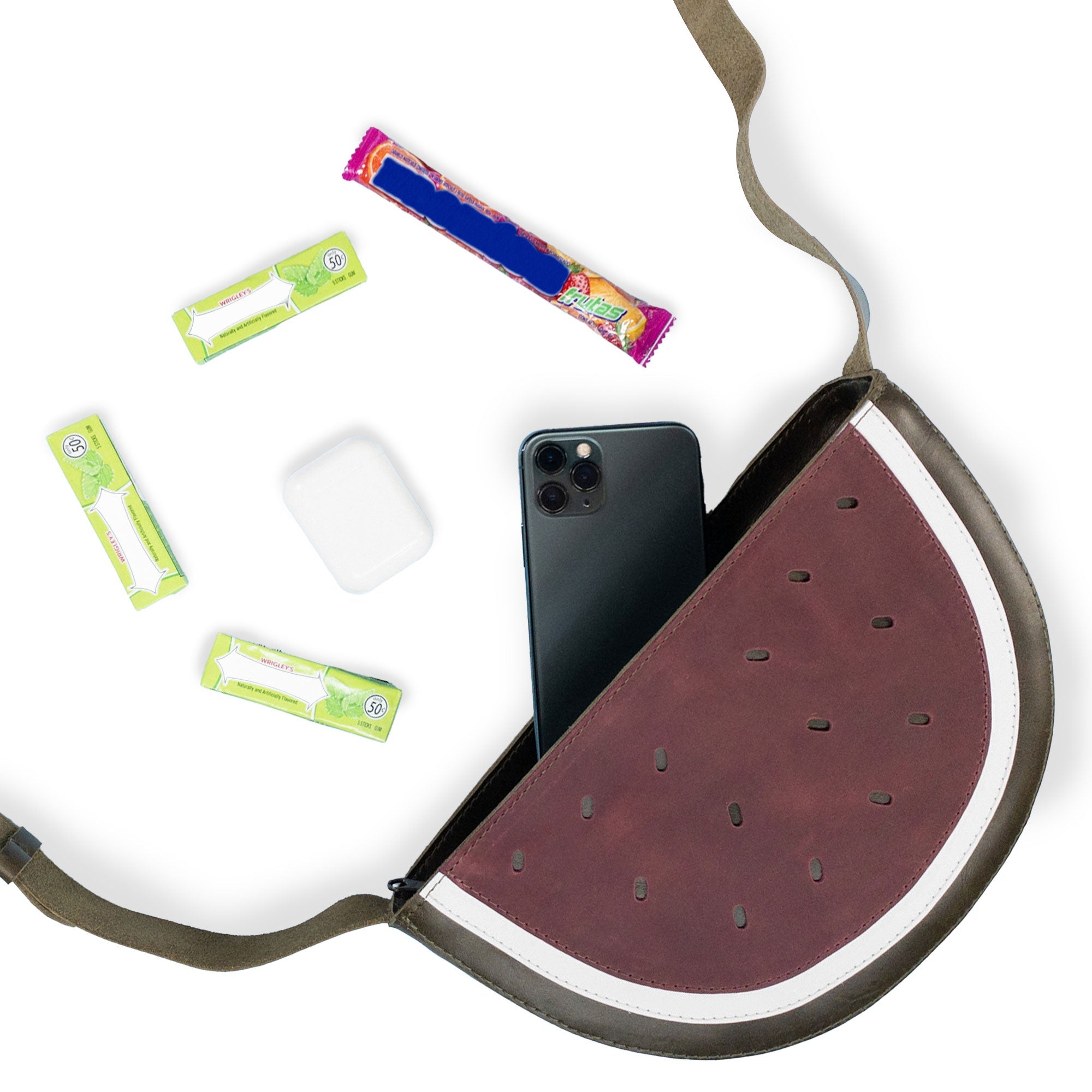 Inside view of the Watermelon-Shaped Shoulder Bag by Tudi Frudi with a phone and assorted items, demonstrating its practical design as a Crossbody Bag. This Messenger Bag is made from durable Full Grain Leather and reflects artisan craftsmanship through small batch production, hand cut, hand sewn, and fire branded techniques. Handmade in La Antigua Guatemala & Oaxaca Mexico.