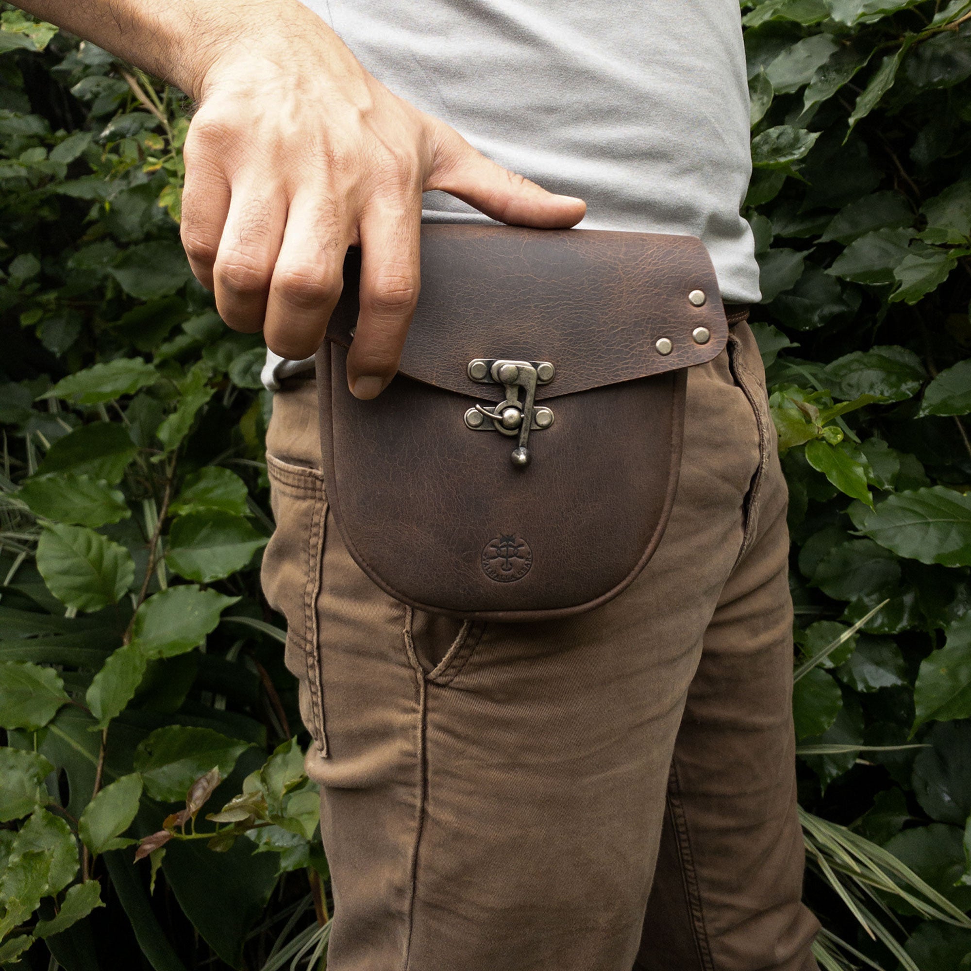 A person holding the Vintage Belt Pouch by Valhalla Gear, featuring a sleek design perfect for carrying small notebooks and everyday items, made from full grain leather, highlighting handmade quality in La Antigua Guatemala.