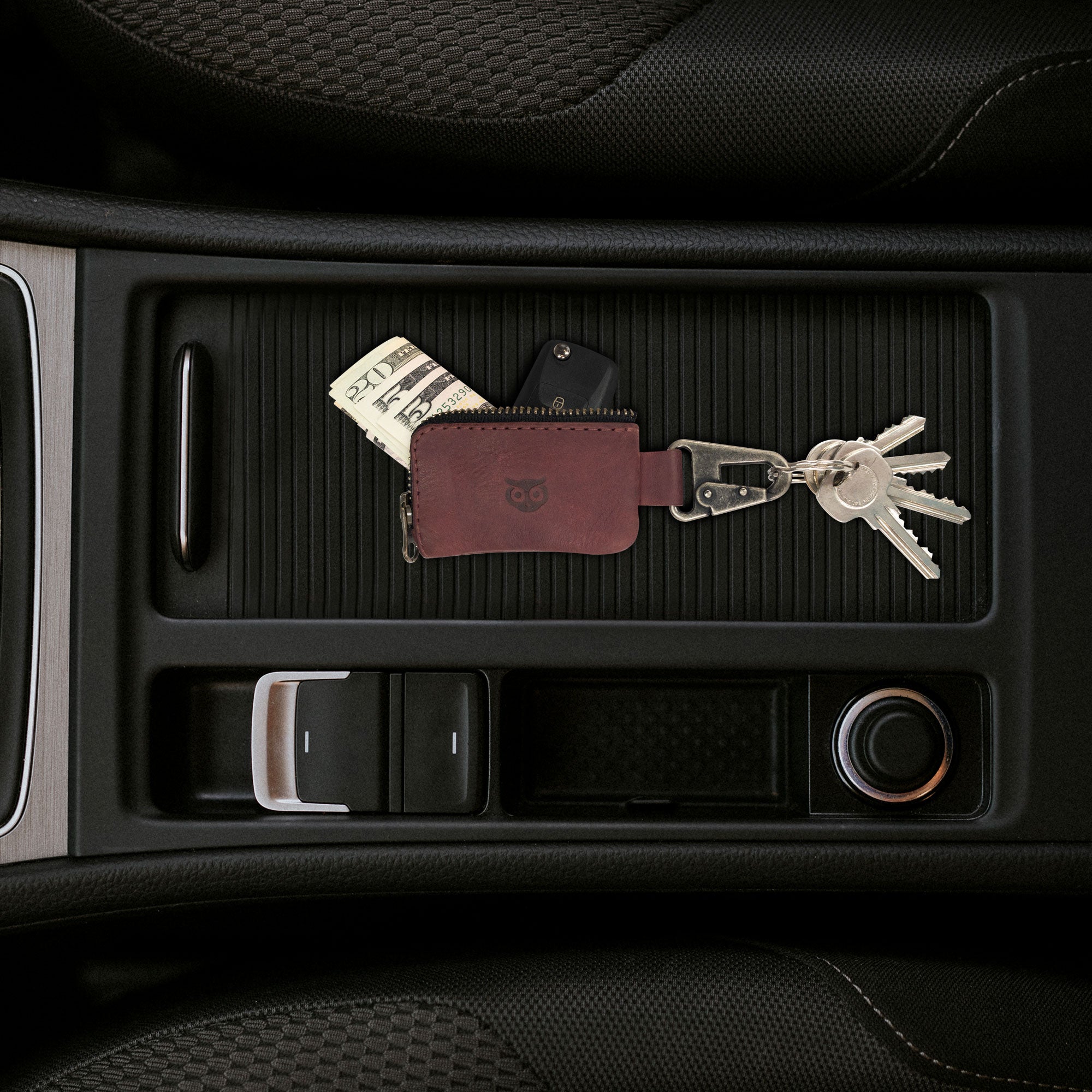 Car Key Holder in a car console by Hide & Drink, showcasing how it can stylishly secure keys while also accommodating Headphone and charging Cables, Memory Cards, and Flash Drives. This Premium Full Grain Leather case, with its Nickel Metal Clasp, highlights the quality craftsmanship from Small Batch Production in La Antigua Guatemala & Oaxaca Mexico.