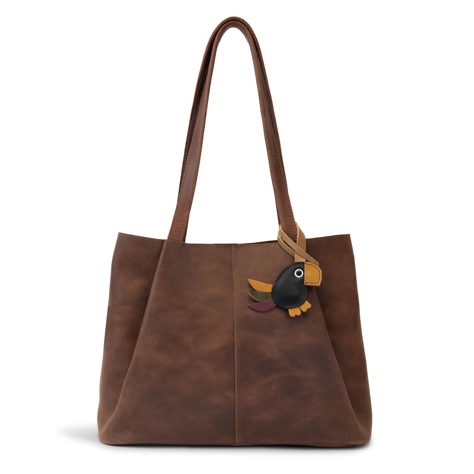 Hide & Drink Bag Charms attached to a stylish brown handbag, displaying a luchador mask design perfect for personalization. This accessory serves as a purse charm for tote & backpacks crafted from durable full grain leather, showcasing StockyardX's commitment to small batch production. Each piece showcases hand cut, hand sewn artistry and fire branding, handmade in La Antigua Guatemala & Oaxaca Mexico.