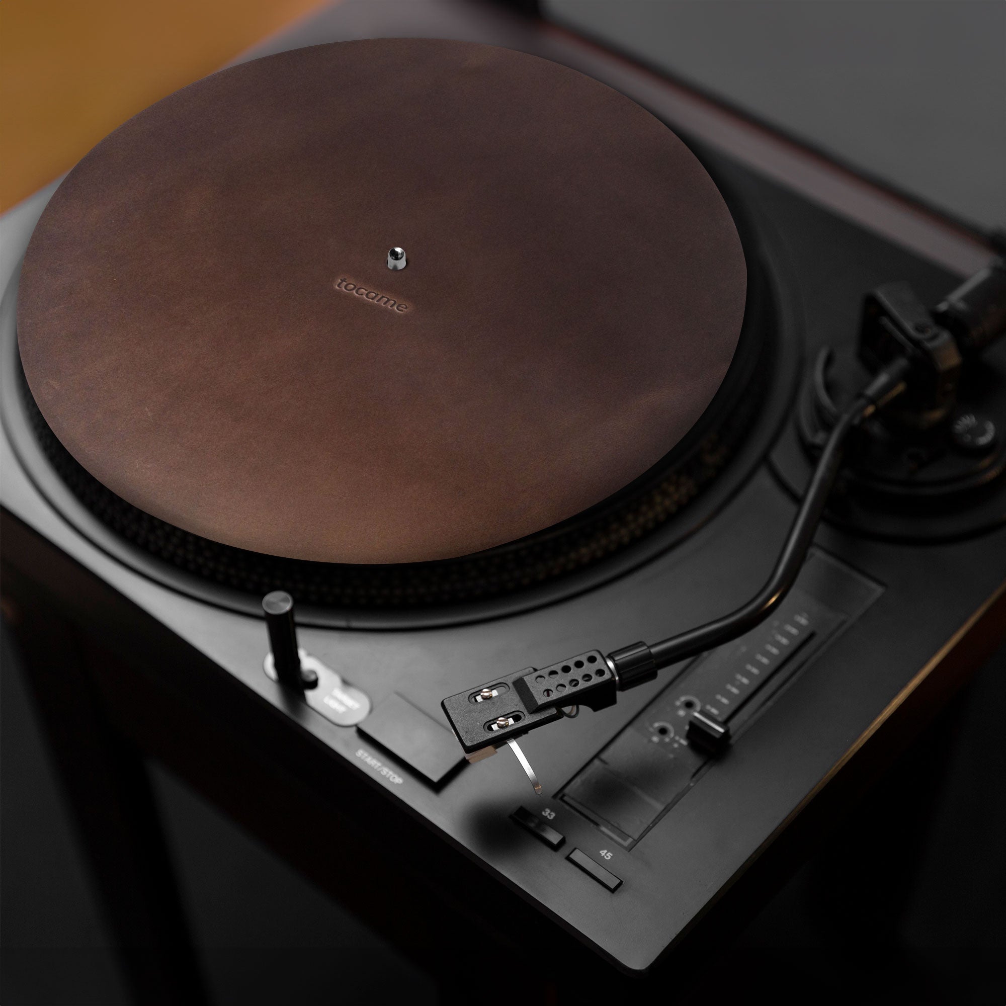 Artistic perspective of tocame's Circular Turntable Slipmat on a turntable, emphasizing its elegant design. This handmade slipmat, crafted from full grain leather, features an antistatic cover that reduces dust and noise for an enhanced listening experience. Artisan-made in La Antigua Guatemala.