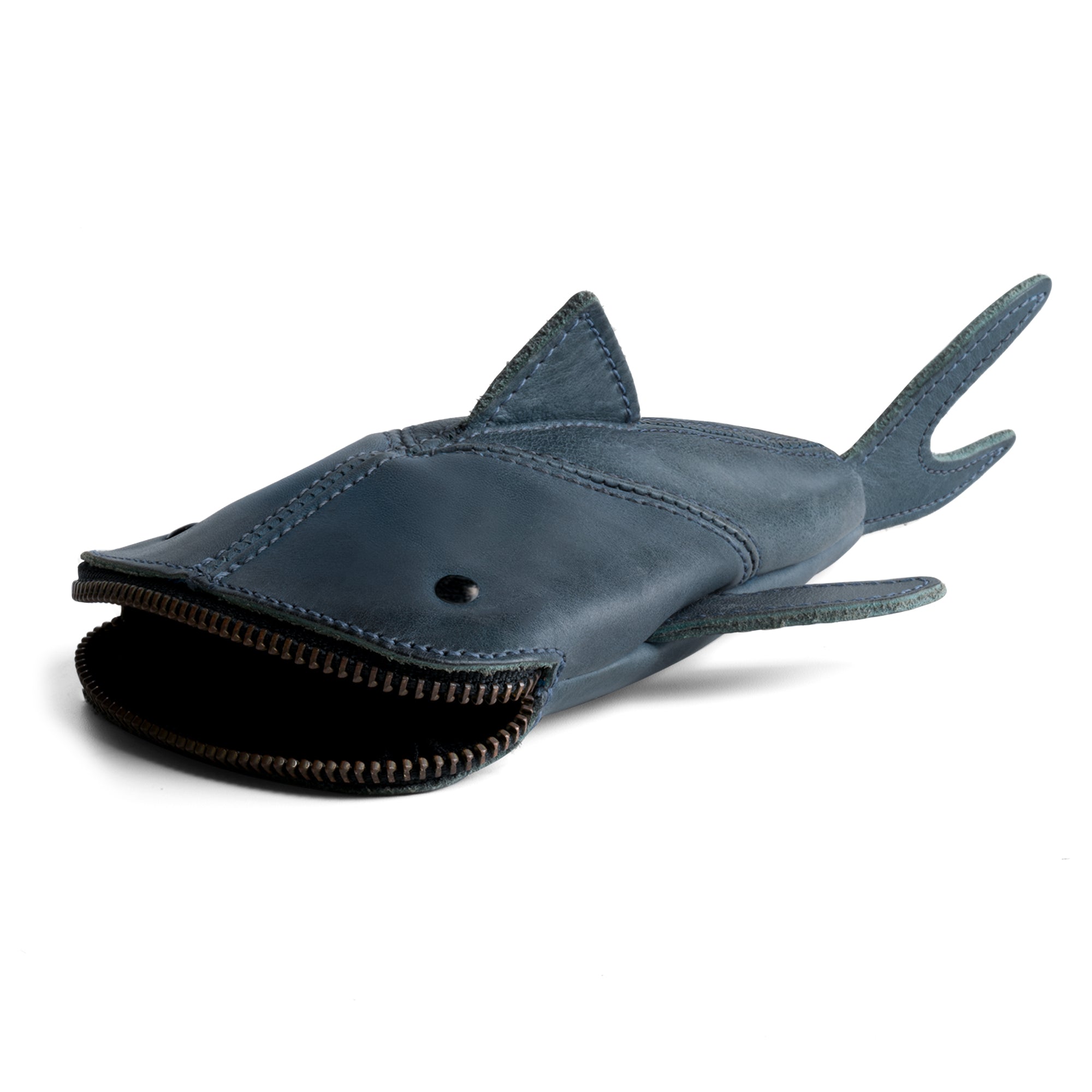 The Leather Shark Pouch by Hide & Drink in blue, featuring a unique zippered design. Ideal for holding stationary, this shark shaped case serves as an excellent pencil purse or zipper coin pouch. Crafted from full grain leather, it's handmade in La Antigua Guatemala & Oaxaca Mexico, exemplifying artisan quality and small batch production.
