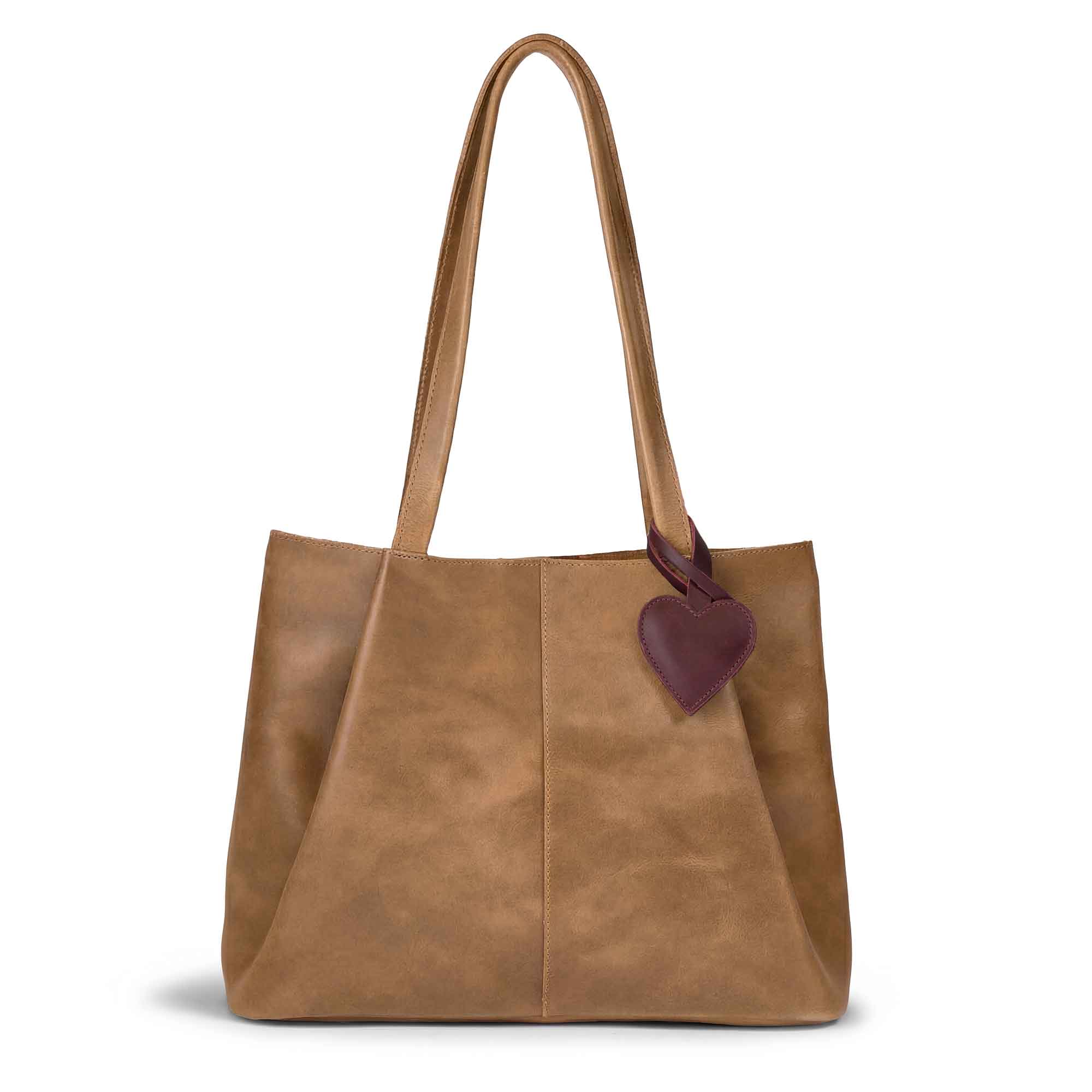 Hide & Drink Bag Charms attached to a stylish brown handbag, showcasing a moose design ideal for personalization. This accessory serves as a purse charm for tote & backpacks made from durable full grain leather, reflecting StockyardX's dedication to small batch production. Every piece features hand cut, hand sewn craftsmanship and fire branding, handmade in La Antigua Guatemala & Oaxaca Mexico.