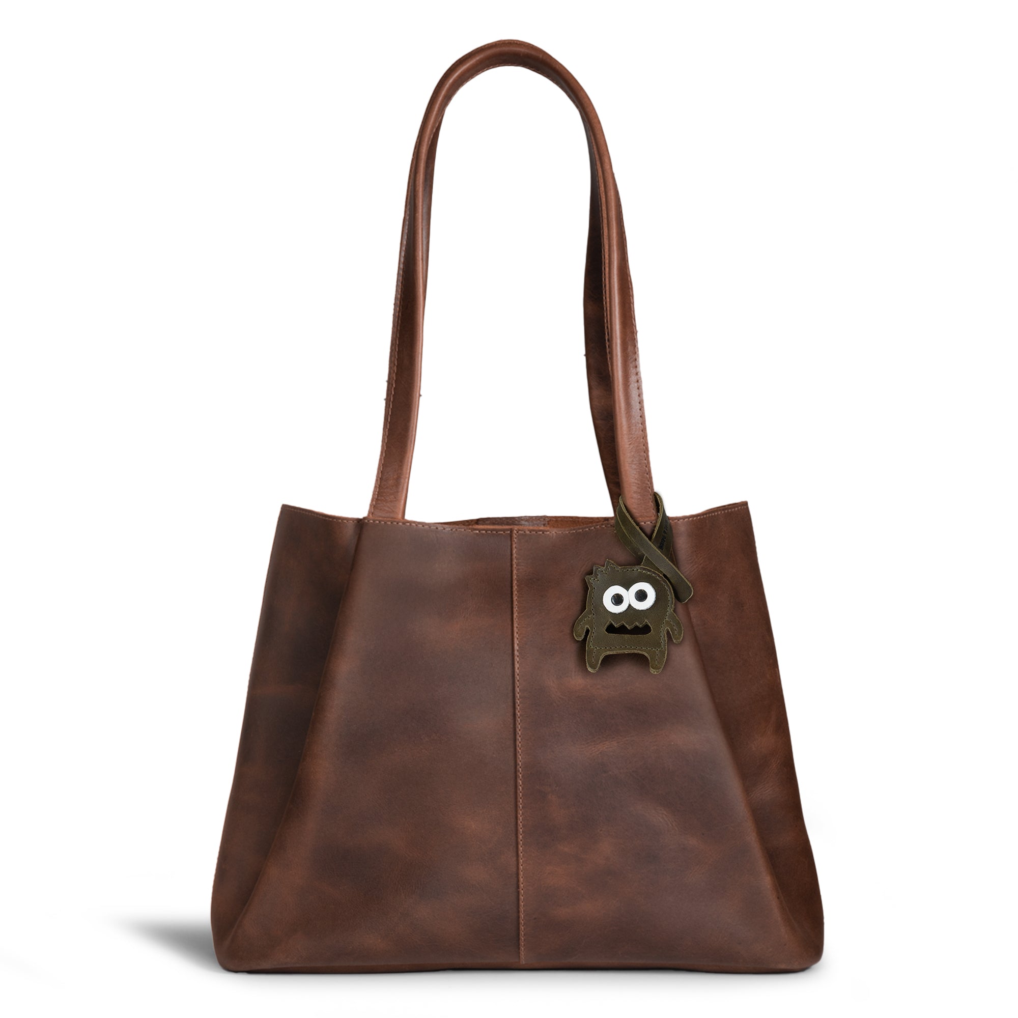 Hide & Drink Bag Charms attached to a fashionable brown handbag, showcasing a cactus design ideal for personalization. This accessory acts as a purse charm for tote & backpacks made from durable full grain leather, demonstrating StockyardX's small batch production ethos. Each item reflects meticulous hand cut, hand sewn details and fire branding, handmade in La Antigua Guatemala & Oaxaca Mexico.