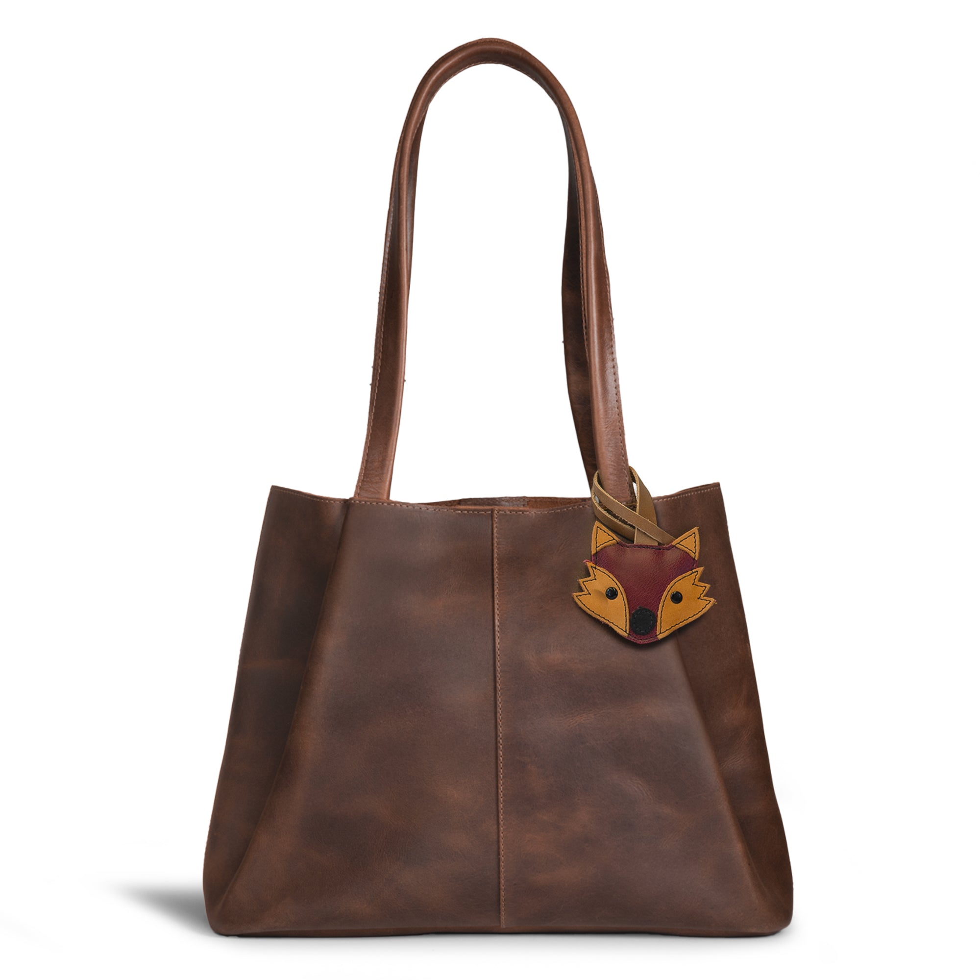 Hide & Drink Bag Charms attached to a trendy brown handbag, featuring a ladybug design ideal for personalization. This accessory serves as a purse charm for tote & backpacks crafted from high-quality full grain leather. Every piece reflects StockyardX's focus on small batch production, showcasing hand cut, hand sewn artistry and fire branding, handmade in La Antigua Guatemala & Oaxaca Mexico.