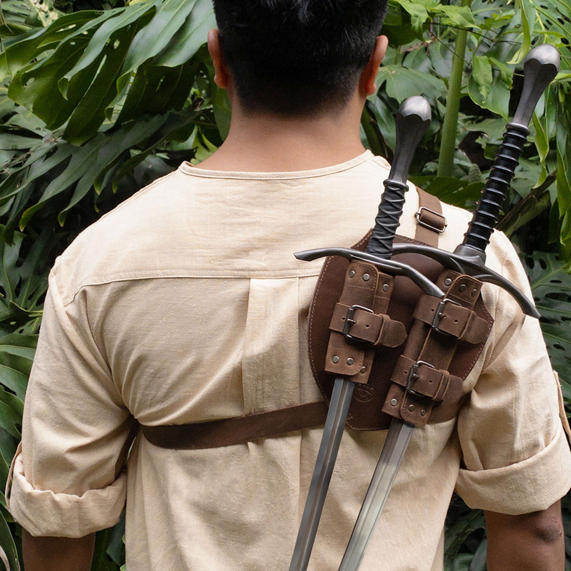 A person wearing the Medieval Back Double Sword Shoulder Frog from Valhalla Gear, demonstrating its use as a stylish full grain leather sheath holster for knight cosplay or warrior costume. This handmade piece reflects small batch production and artisan skills from La Antigua Guatemala.