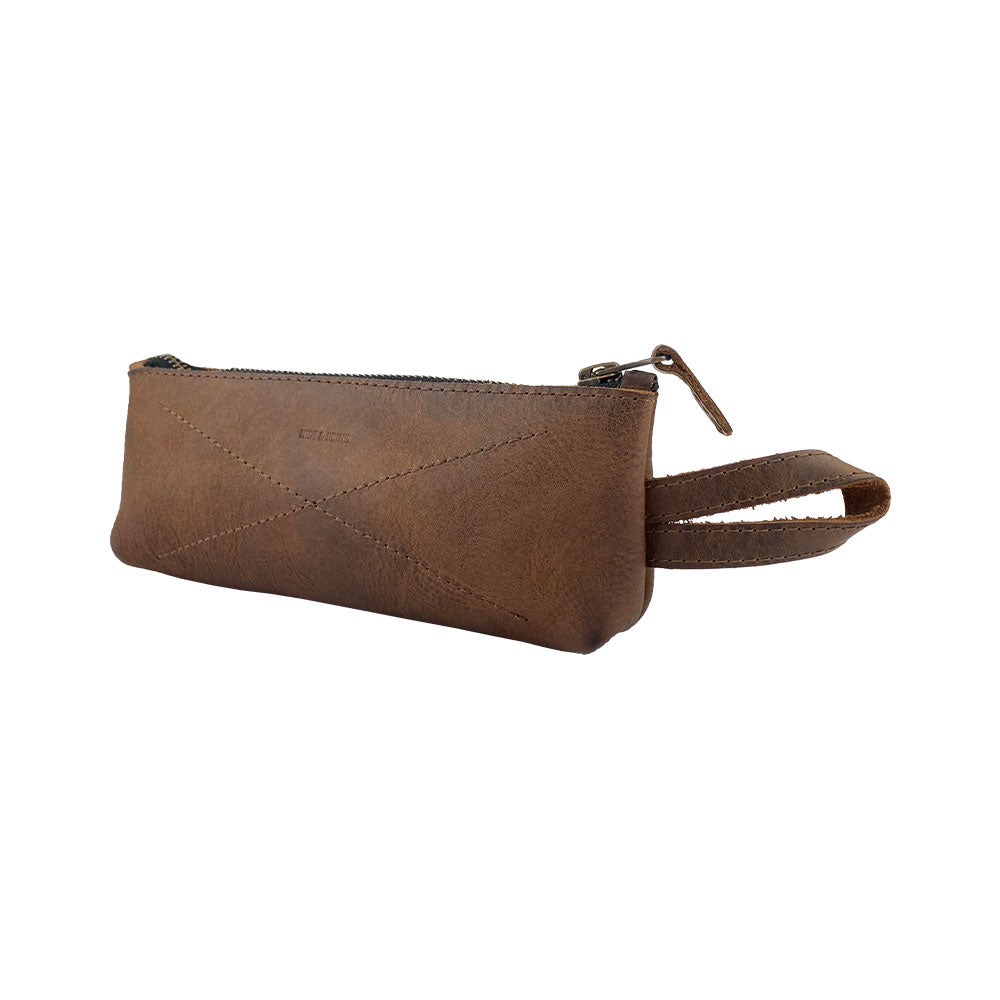 Hide & Drink's X Stitched Case, designed for storing pens and pencils, showcases a rustic full grain leather finish. Ideal as a cable organizer, this artisan-crafted piece is handmade in La Antigua Guatemala and Oaxaca, Mexico.