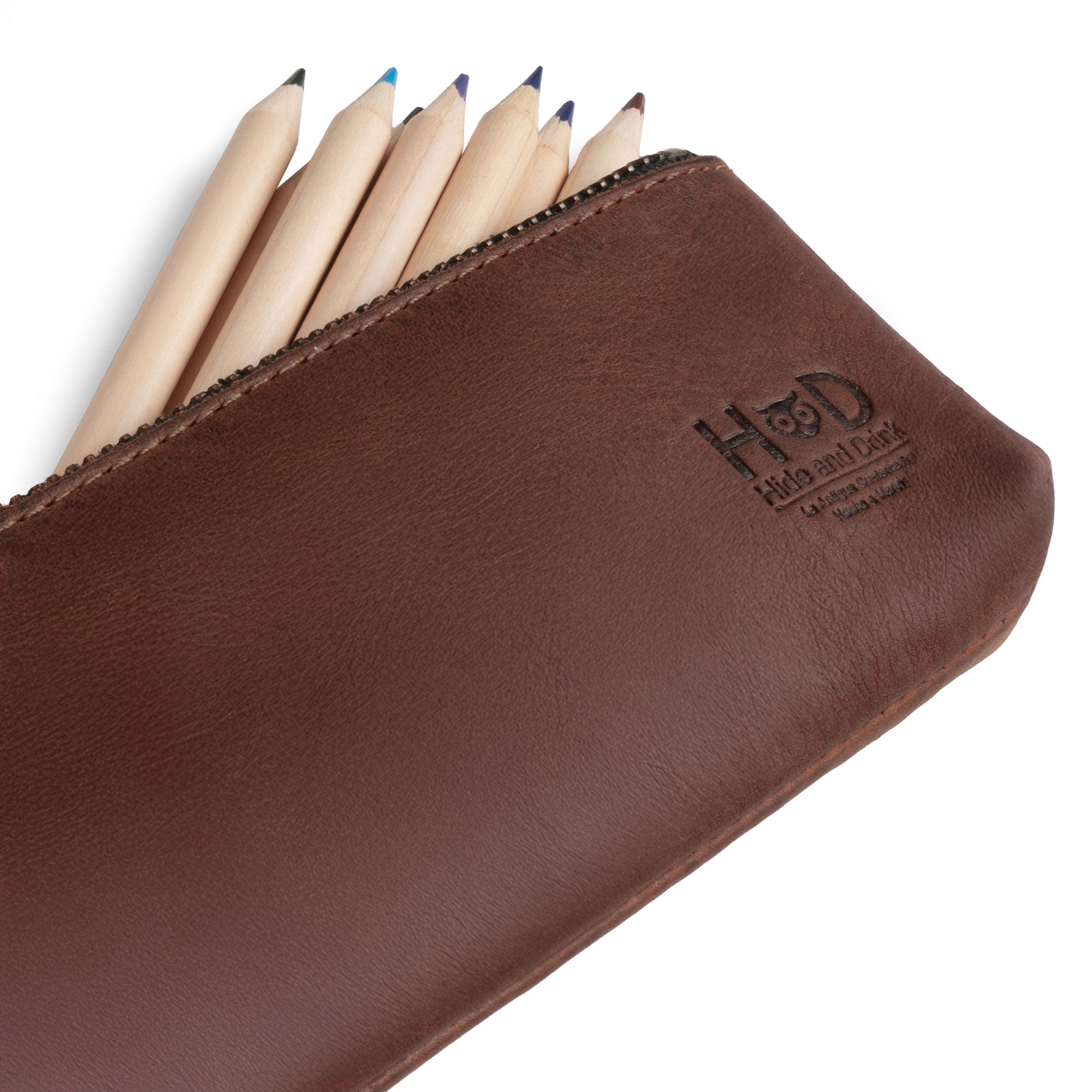 Hide & Drink Pencil Pouch presented alongside pens. This full grain leather rectangular pencil case serves as a pen & marker pouch for both men and women, featuring a flat zippered holder design. Handmade in La Antigua Guatemala & Oaxaca Mexico, and known for small batch production and artisan craftsmanship.