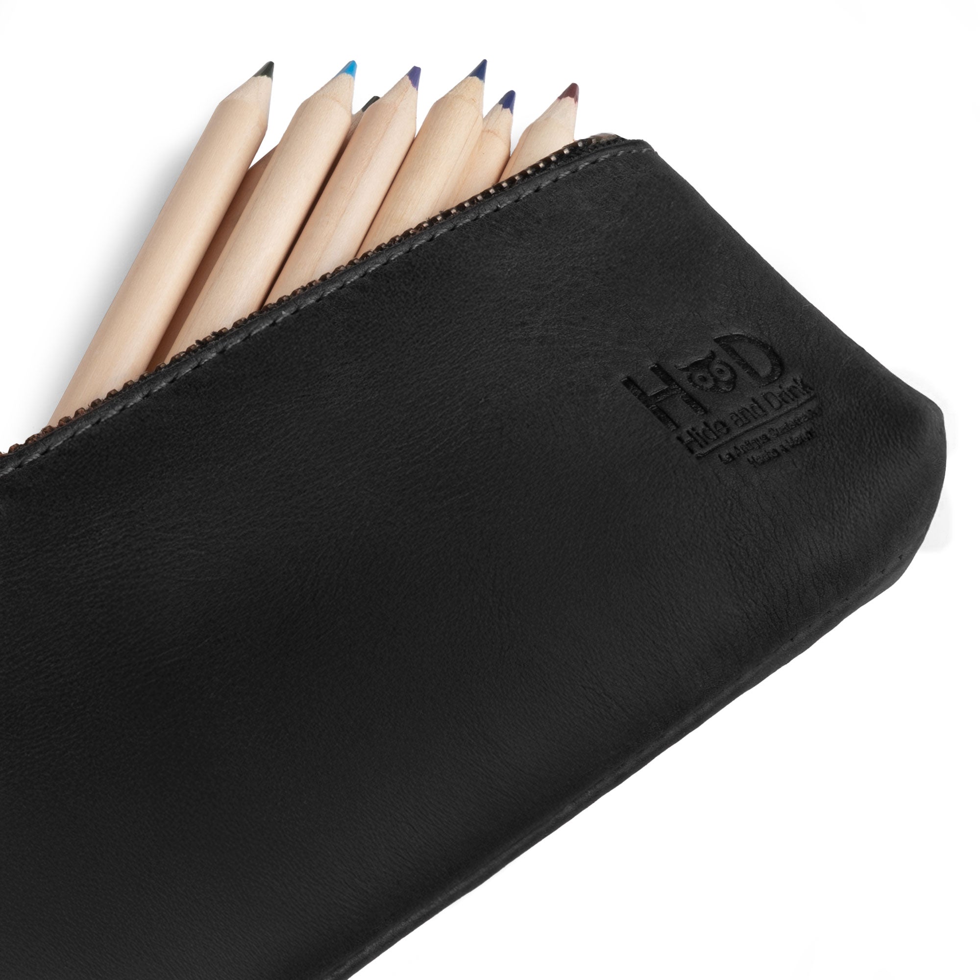 Hide & Drink Pencil Pouch presented alongside pens. This full grain leather rectangular pencil case serves as a pen & marker pouch for both men and women, featuring a flat zippered holder design. Handmade in La Antigua Guatemala & Oaxaca Mexico, and known for small batch production and artisan craftsmanship.
