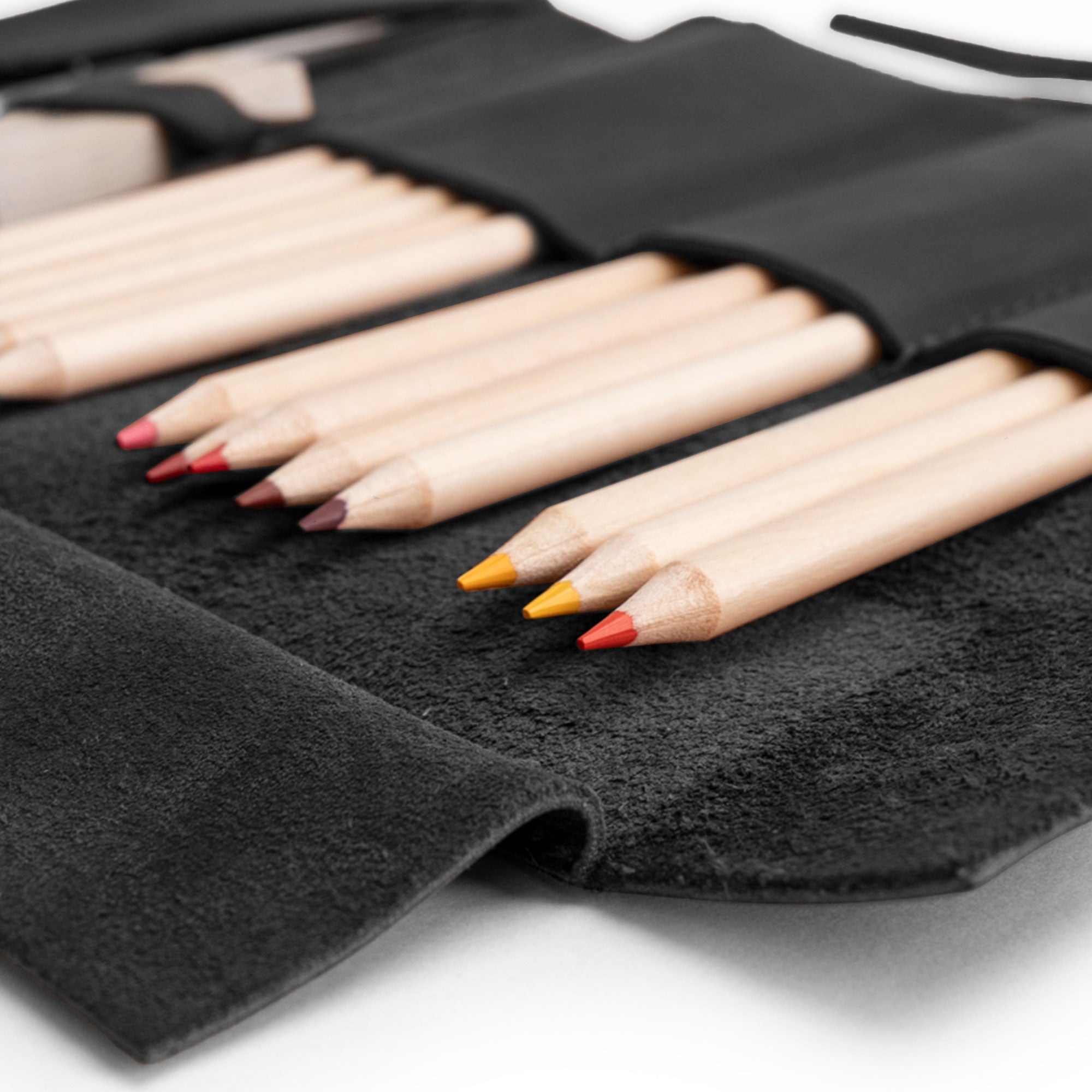 Close-up of colored pencils in the Multi Purpose Pencil Roll from Hide & Drink, made with premium full grain leather. This pencil roll pouch serves as a multi-purpose storage wrap, perfect for organizing work tools, craft items, and earphones, showcasing craftsmanship from artisans in La Antigua Guatemala & Oaxaca Mexico.